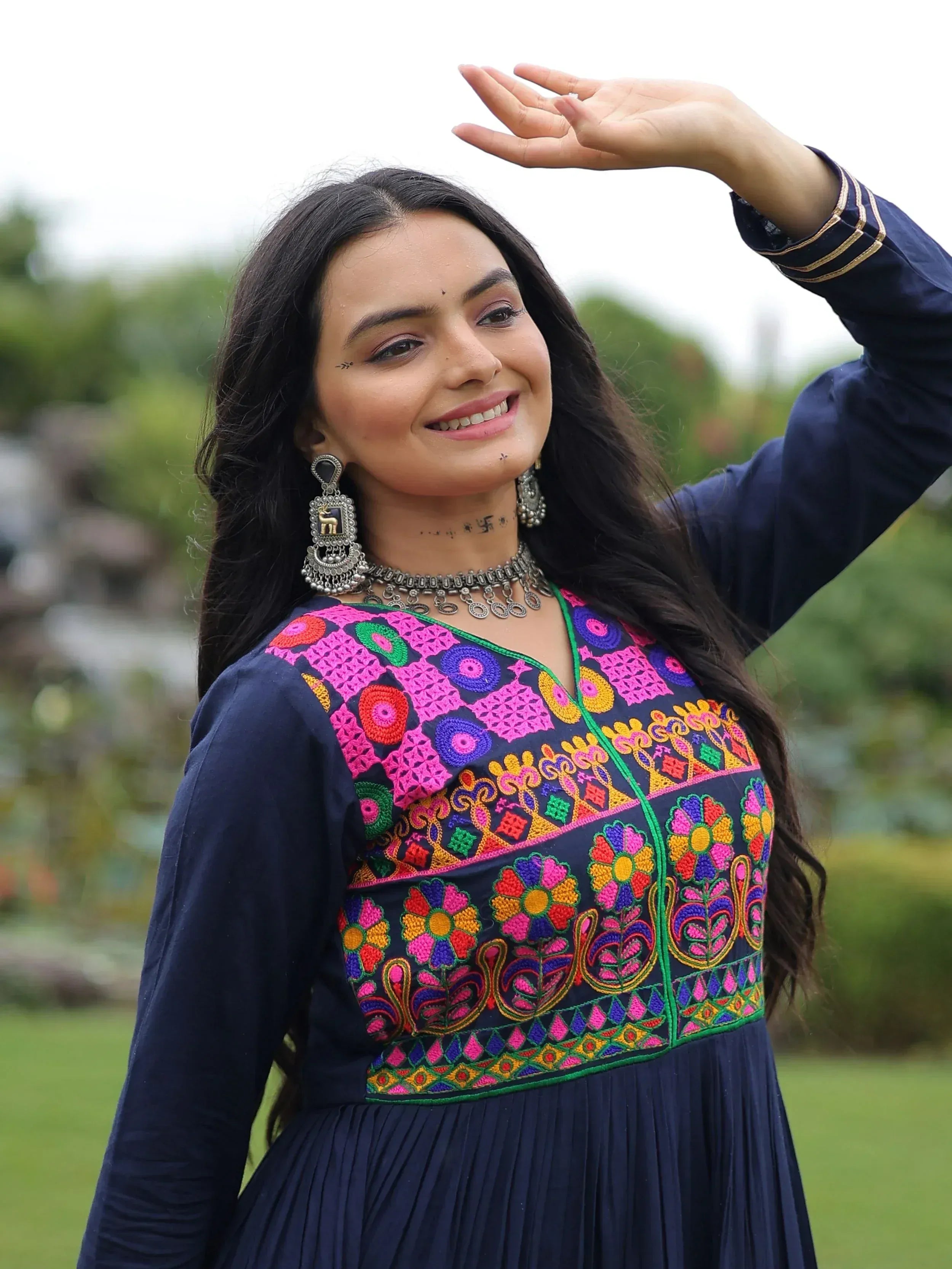 Woman in navy blue ethnic gown with vibrant floral embroidery, perfect for Indian festive occasions.
