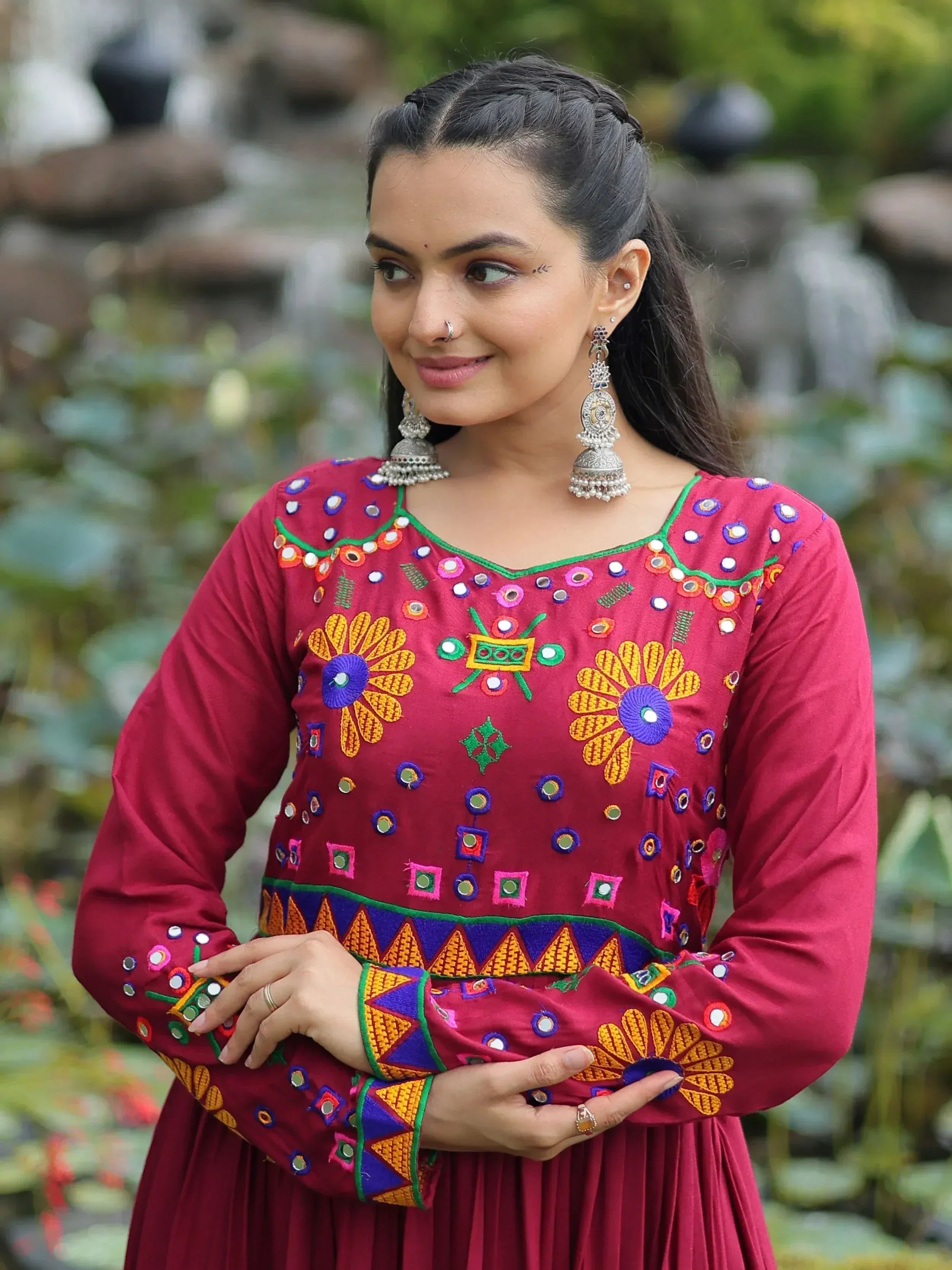 Maroon ethnic gown with mirror work and floral embroidery, paired with jhumka earrings for Indian festive wear