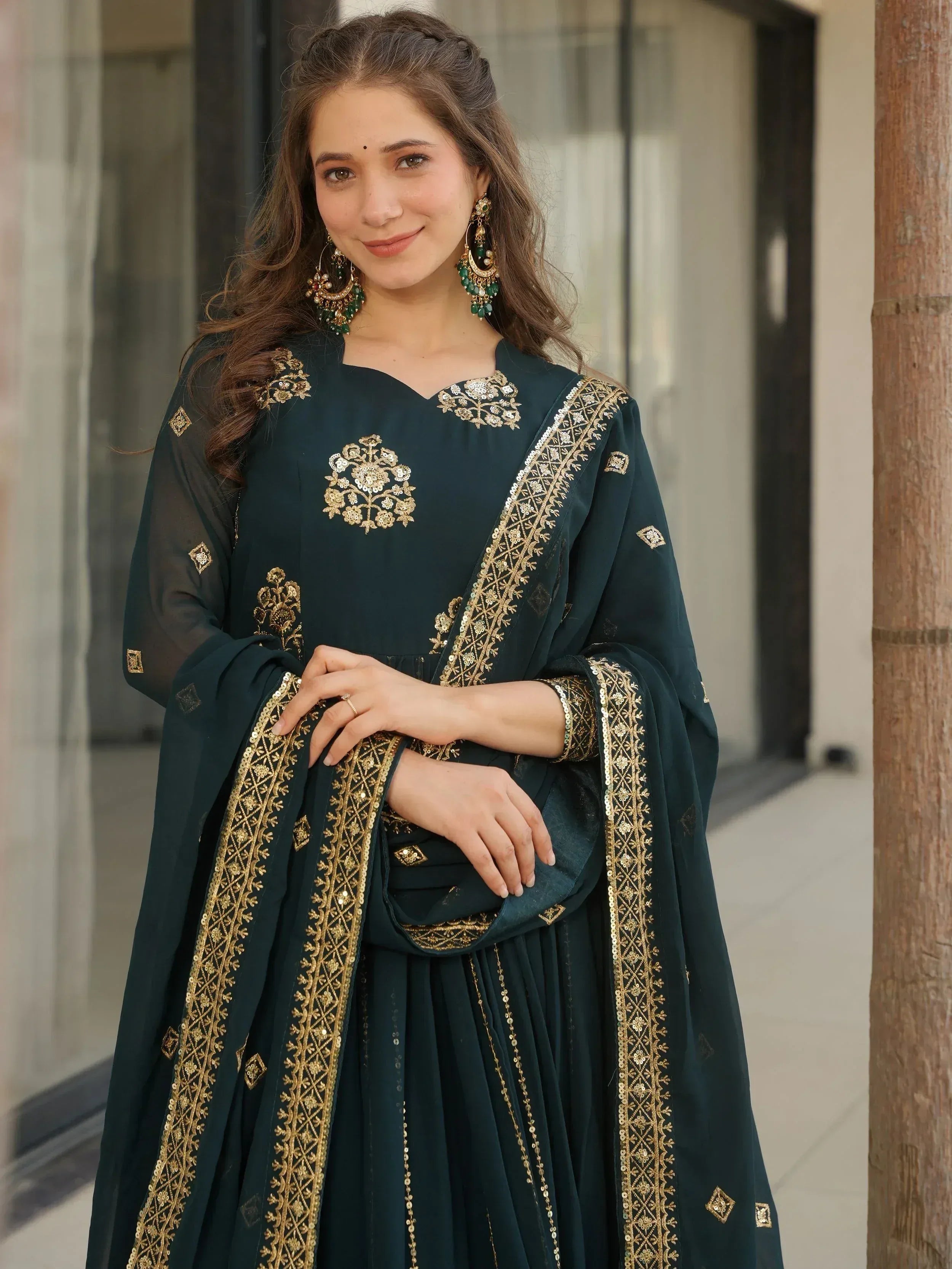 Emerald green ethnic gown with gold embroidery, perfect for Indian weddings or festive occasions.