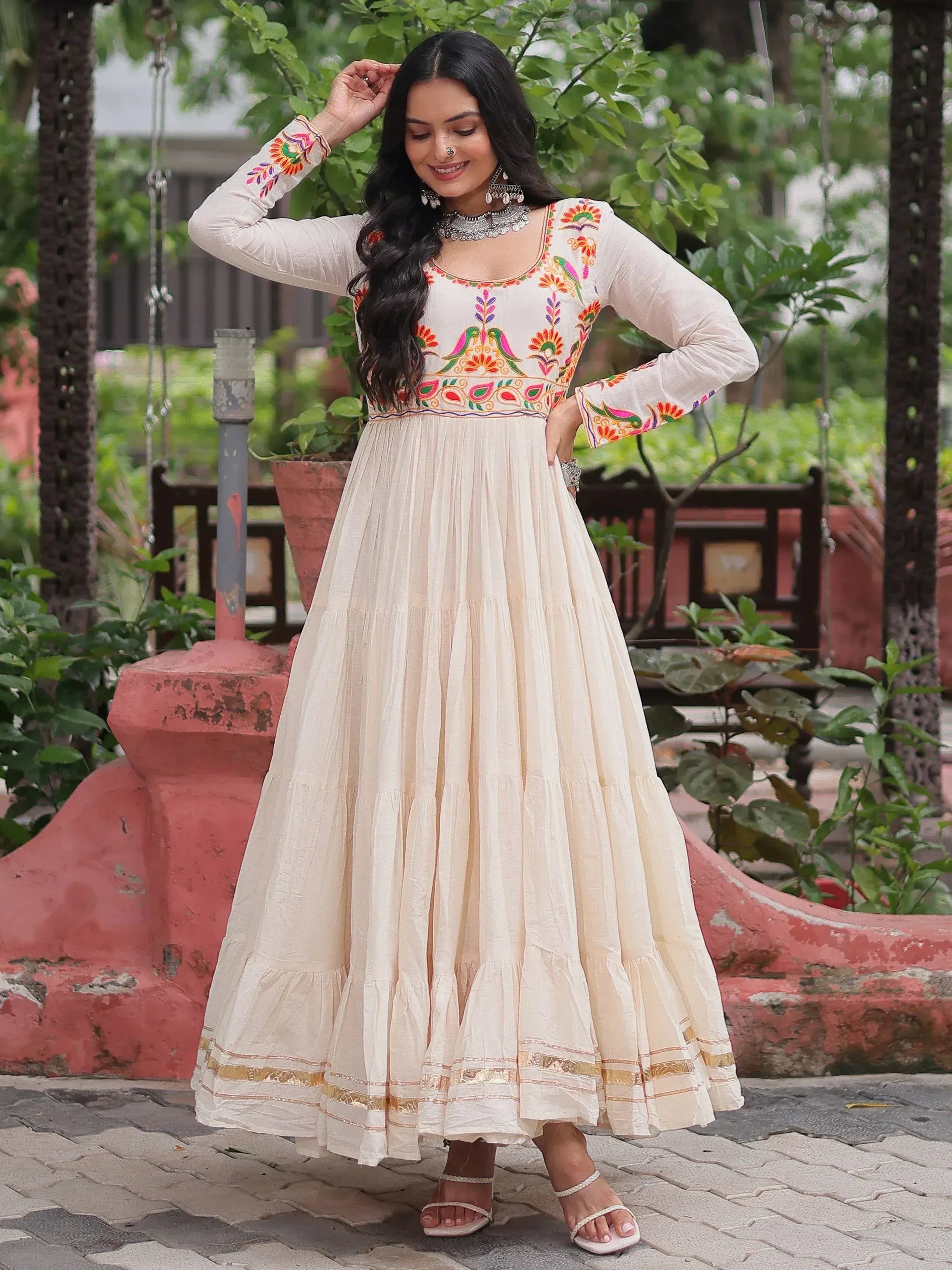 Cream embroidered ethnic gown with colorful floral motifs, perfect for Indian occasions