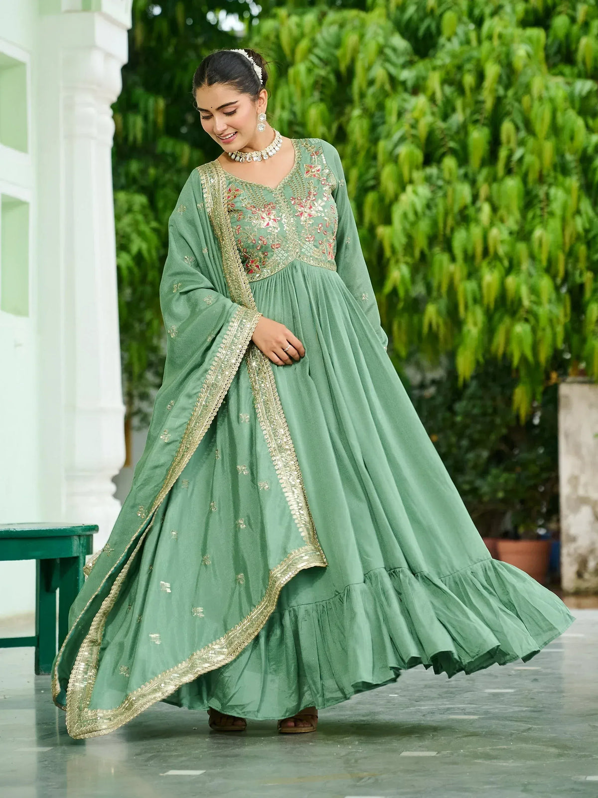 Mint green embroidered anarkali with gold trim, floral detailing, and ruffled hem for festive occasions