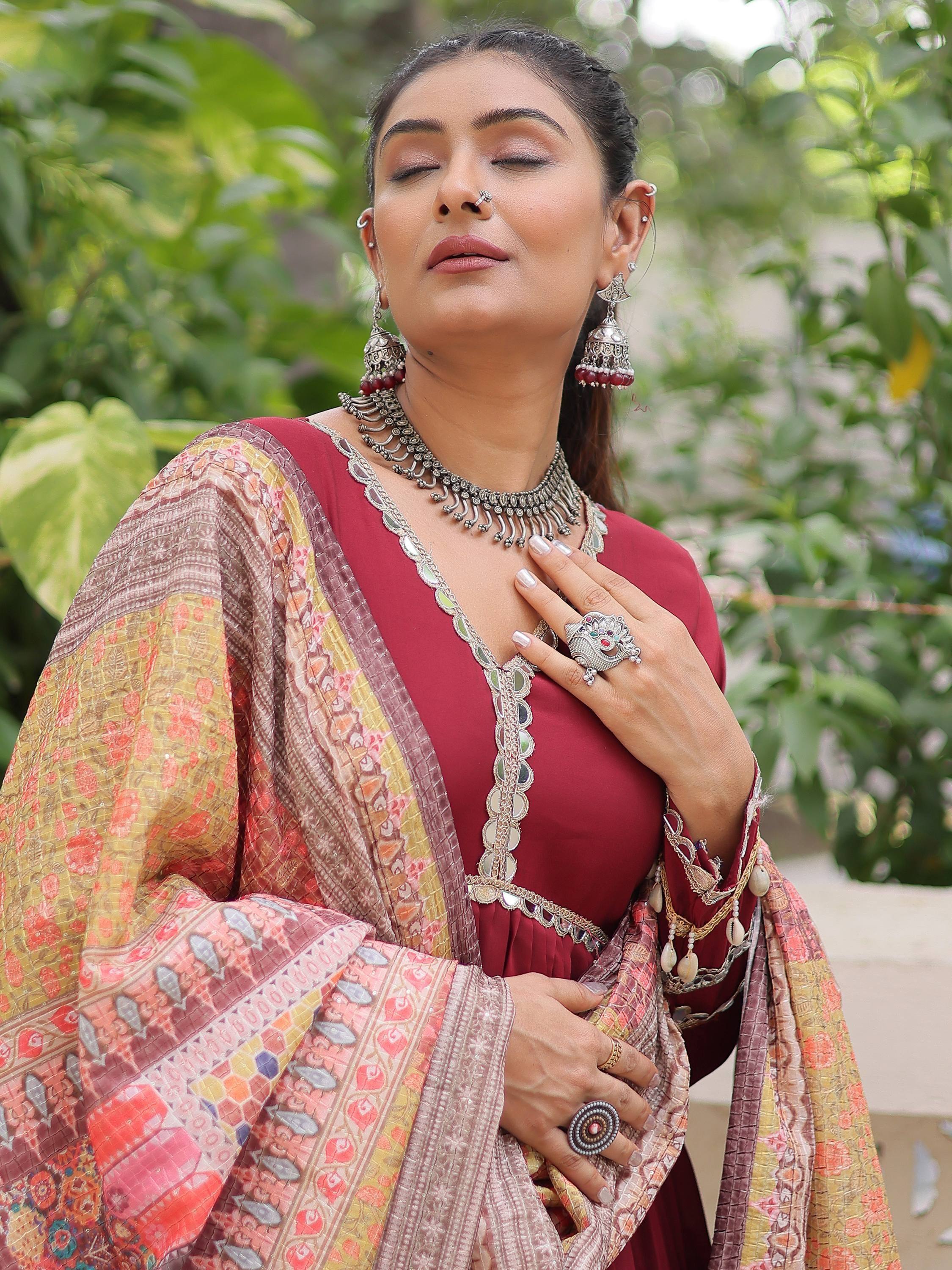 Elegant woman in maroon ethnic gown with intricate embroidery and traditional jewelry