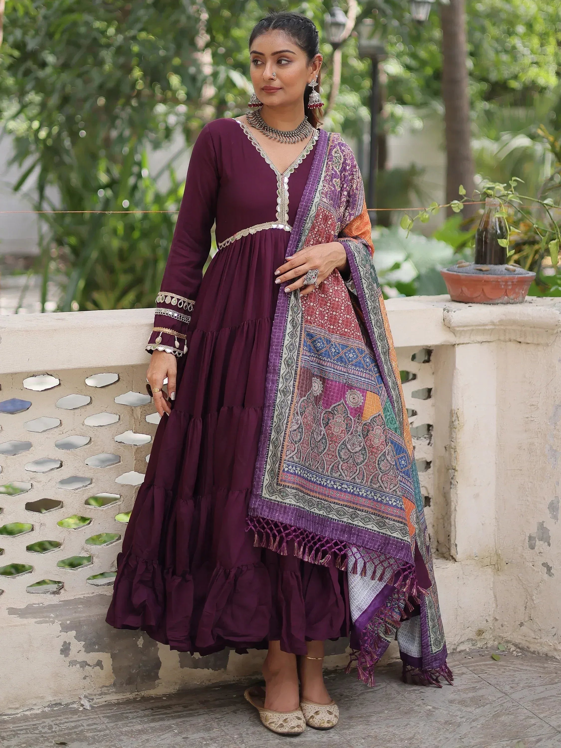 Elegant maroon tiered Anarkali with mirror work, paired with colorful printed dupatta for festive occasions