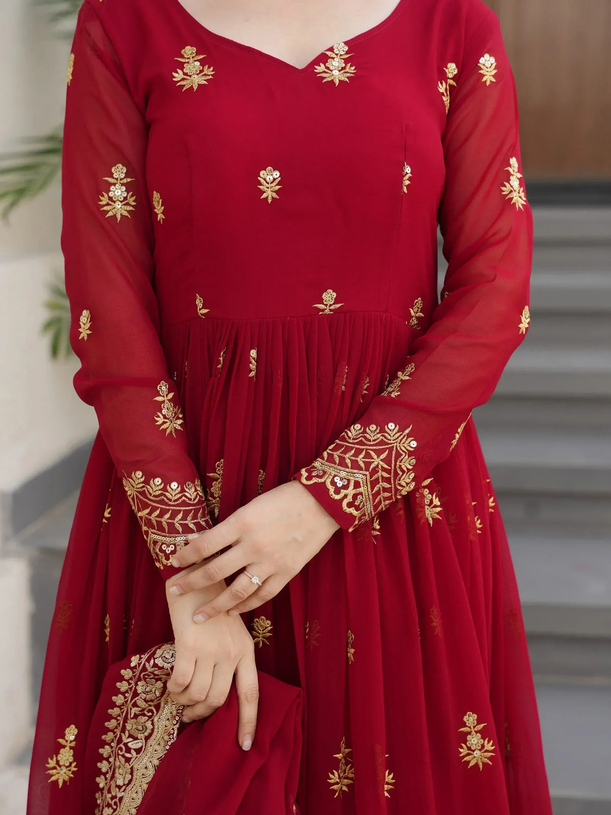 Red ethnic gown with gold floral embroidery and sheer sleeves, perfect for Indian occasions