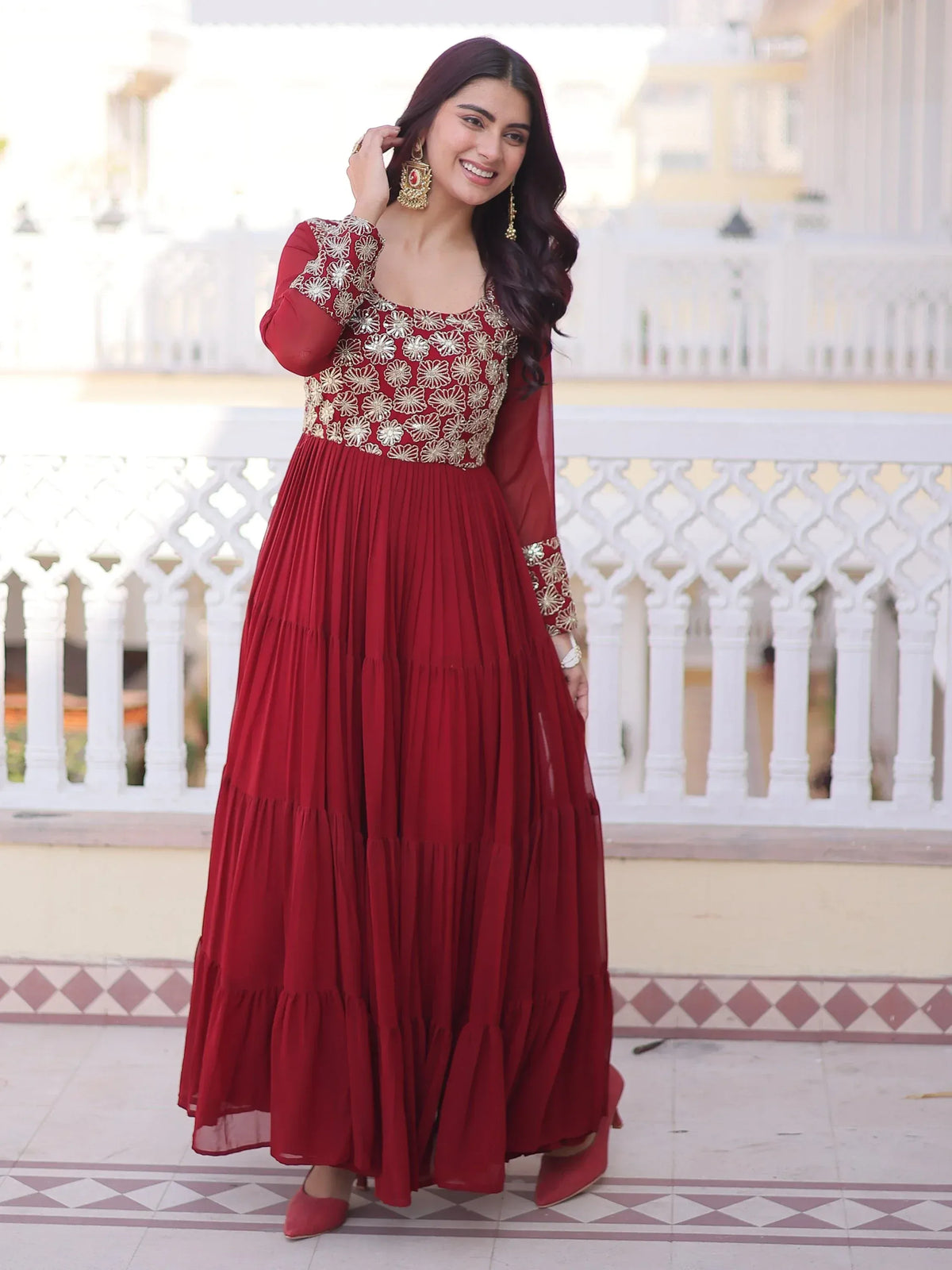 Woman wearing a maroon embroidered ethnic gown with gold detailing
