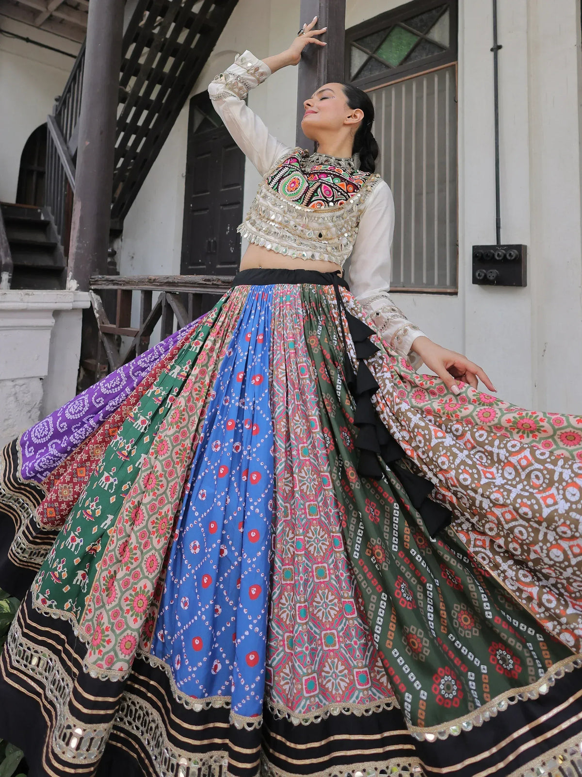 Woman in colorful Indian ethnic lehenga choli with mirror work, standing on balcony