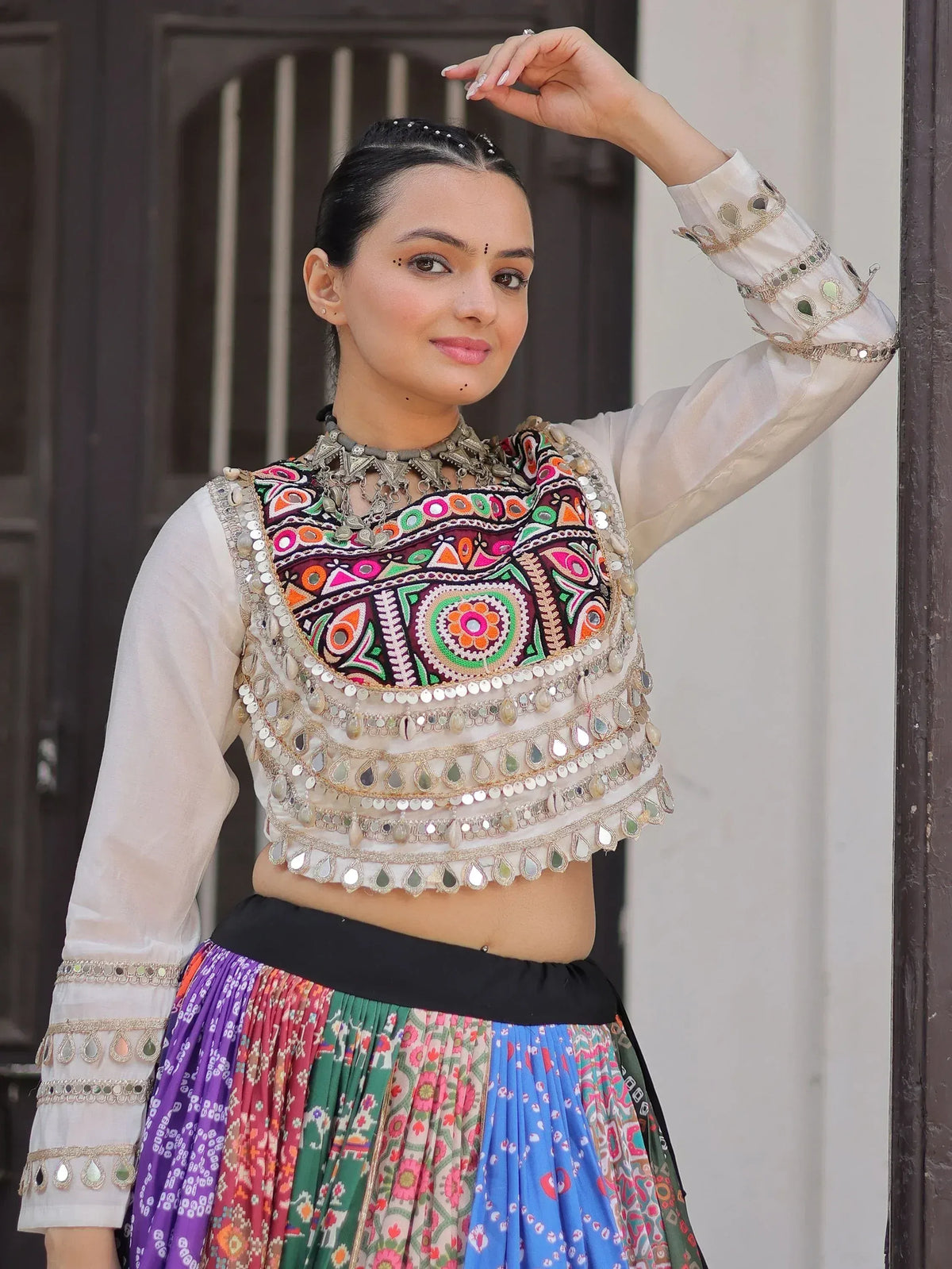 Woman in colorful Indian ethnic wear with mirror work blouse and printed skirt, perfect for festive occasions.