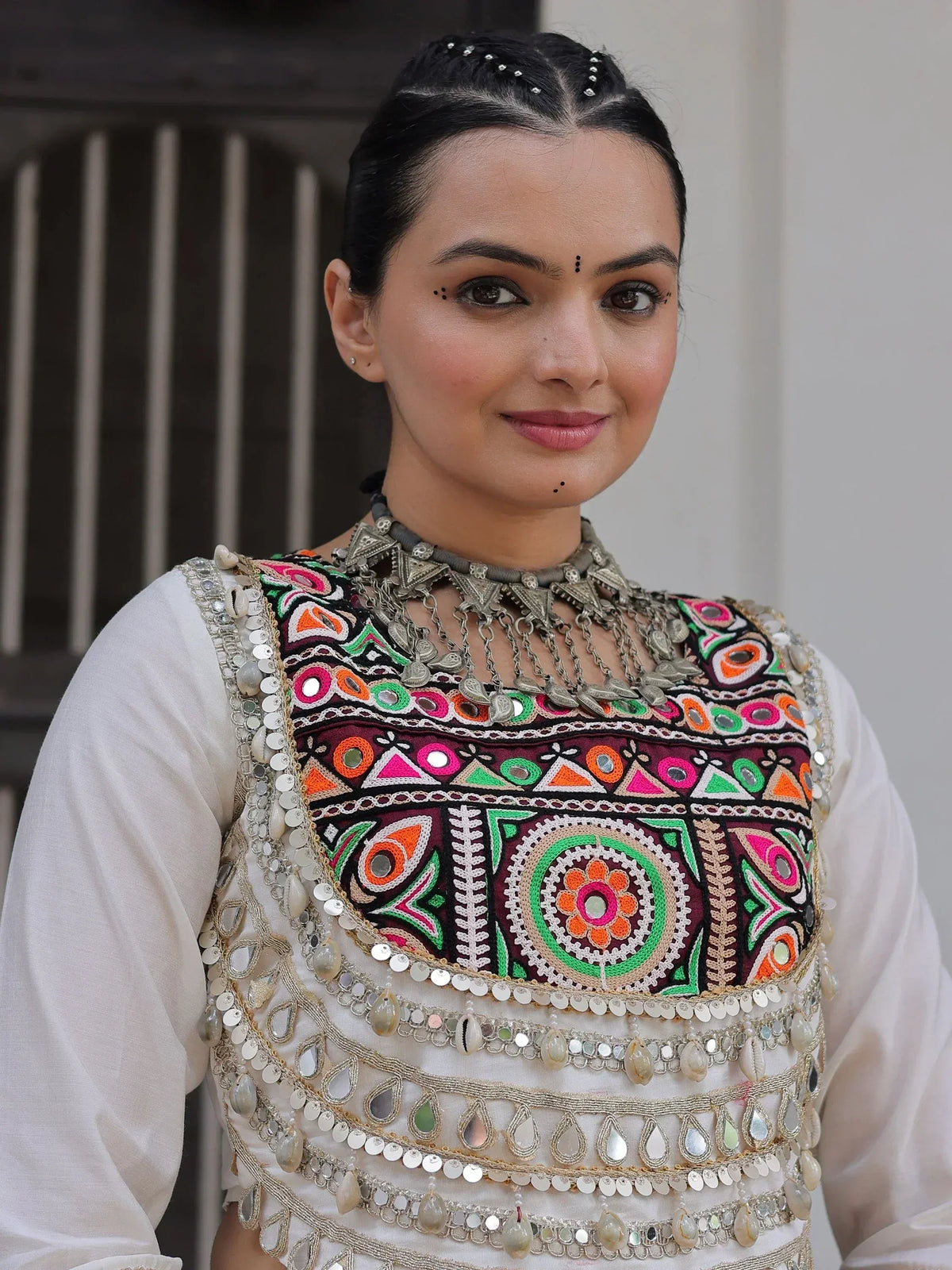 Woman in white ethnic kurti with colorful mirror work and embroidery, traditional Indian attire