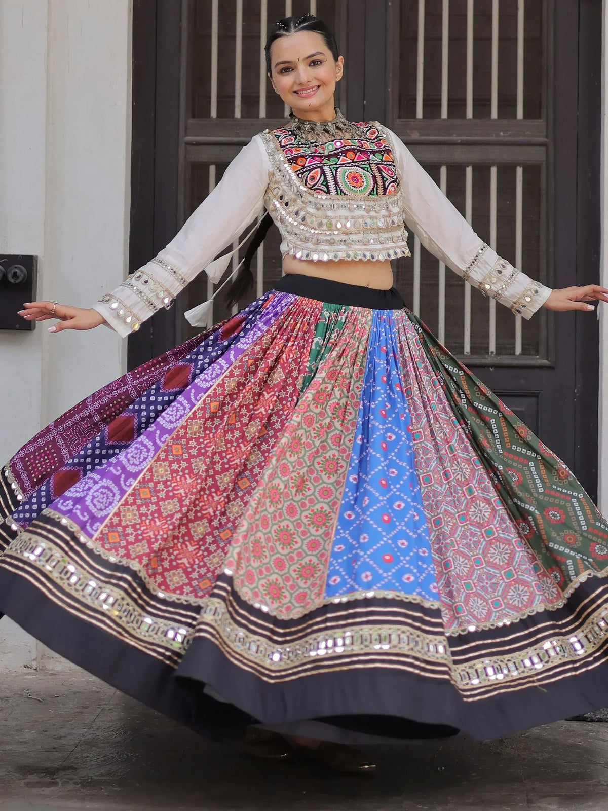 Woman in colorful Indian ethnic wear with mirror work, floral skirt, and embroidered blouse, perfect for festive occasions.