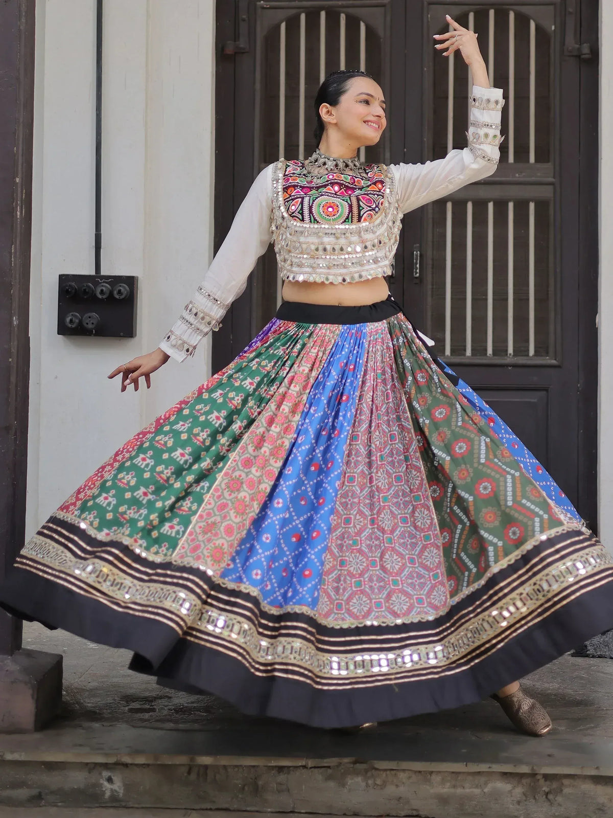 Woman in colorful Indian ethnic wear with mirror work, dancing in front of a door