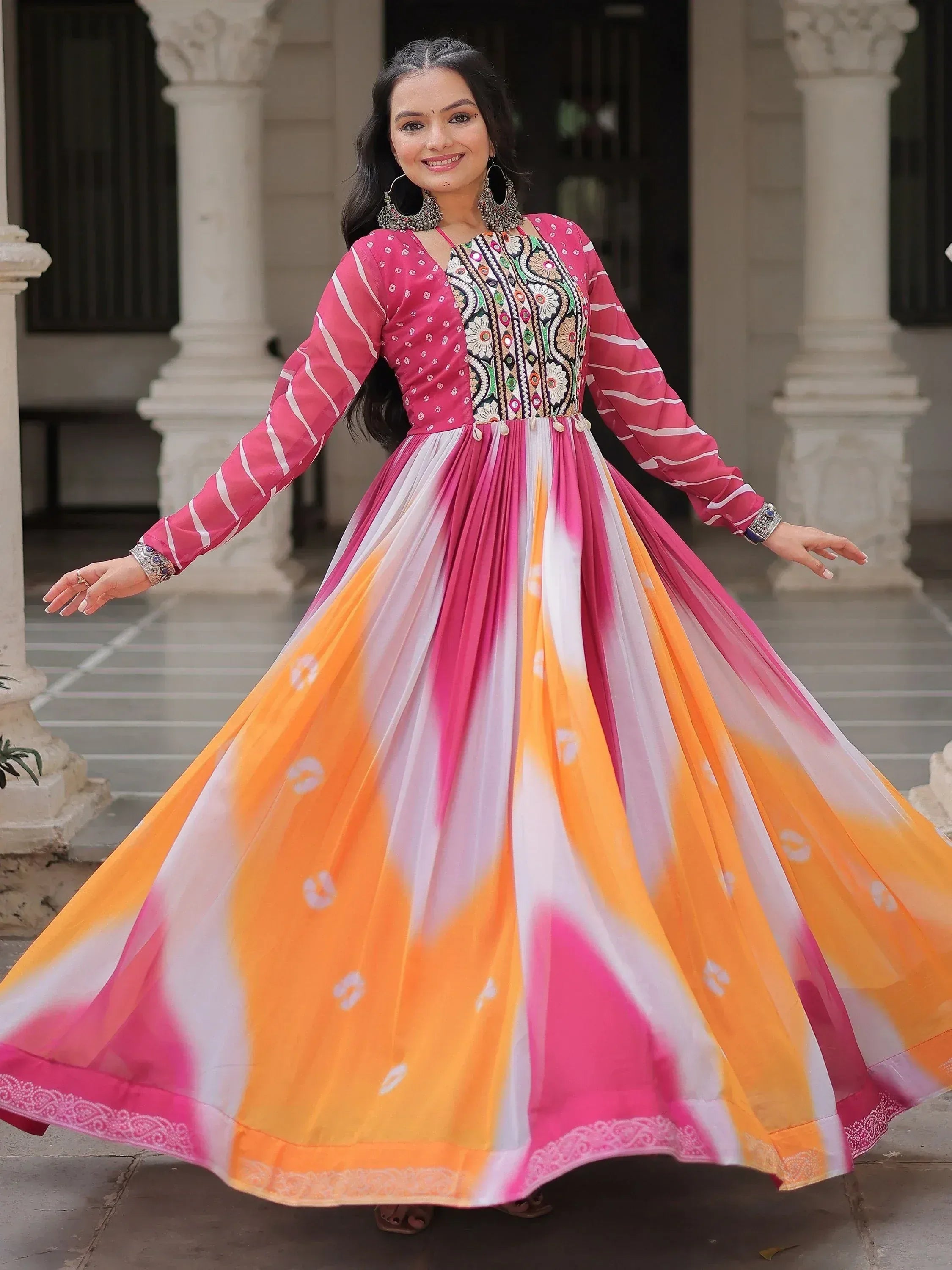 Woman in vibrant pink and orange ethnic gown with embroidered bodice, perfect for festive occasions.