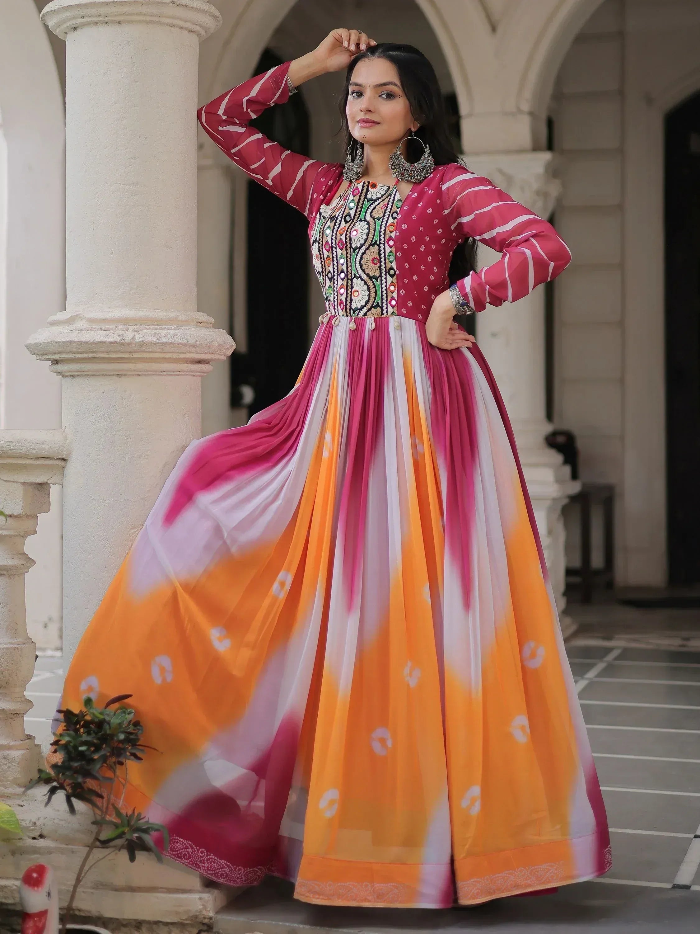Woman in vibrant pink and orange tie-dye ethnic gown with embroidered top, perfect for Indian festive occasions.