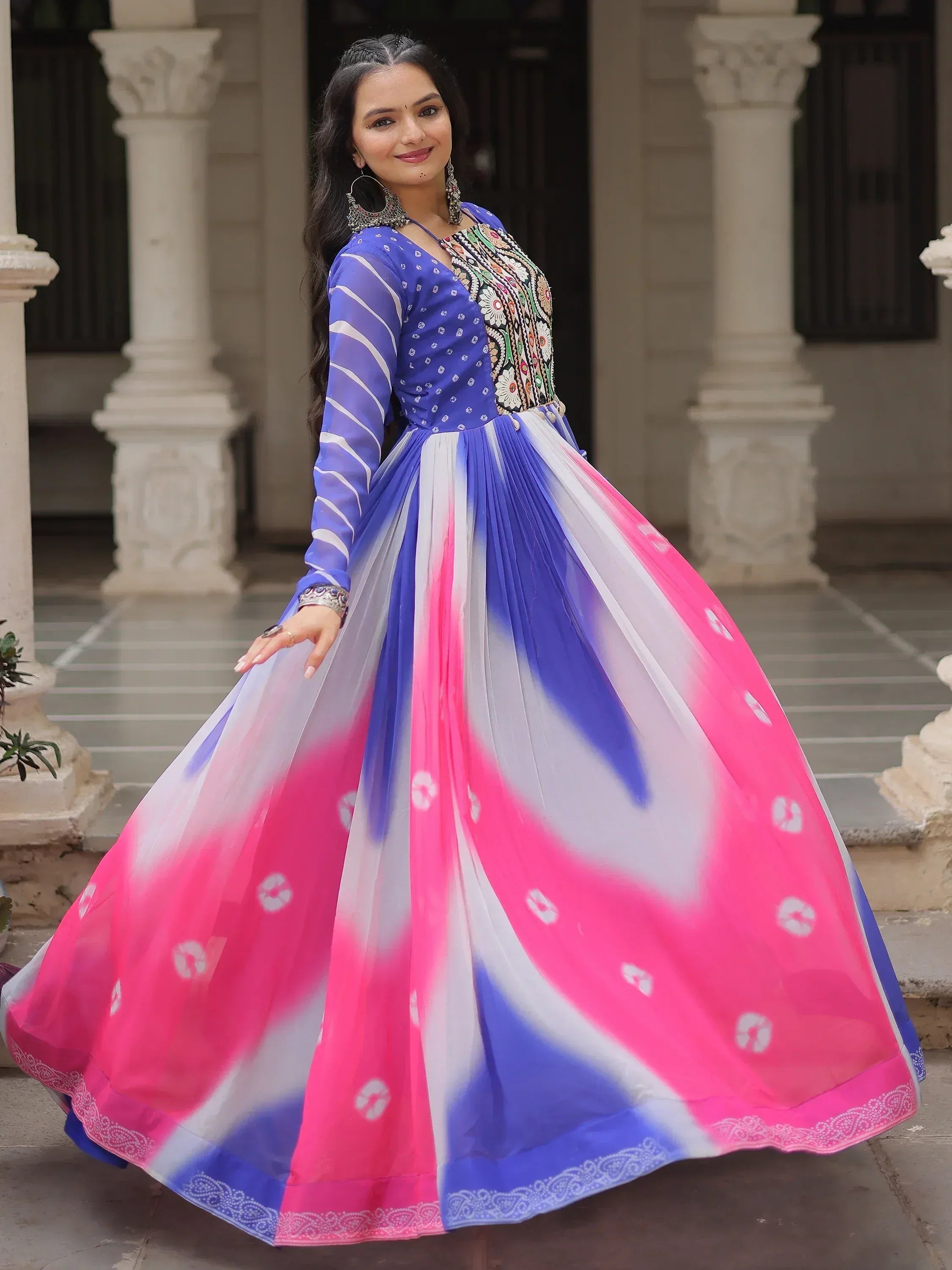 Woman in vibrant blue and pink ethnic gown with floral embroidery, perfect for Indian festive occasions.