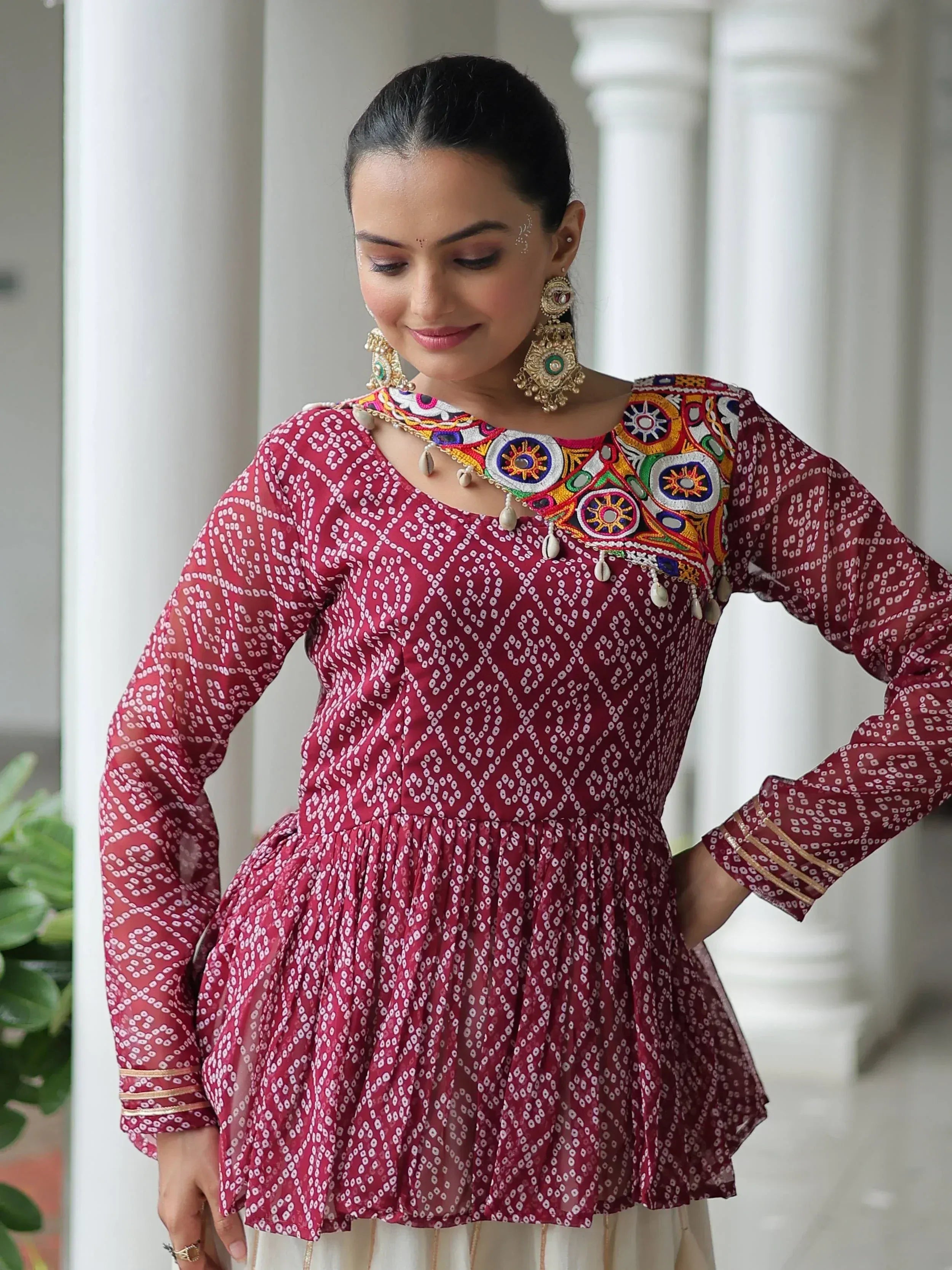 Maroon ethnic kurta with mirror embroidery and printed pattern, paired with traditional jewelry