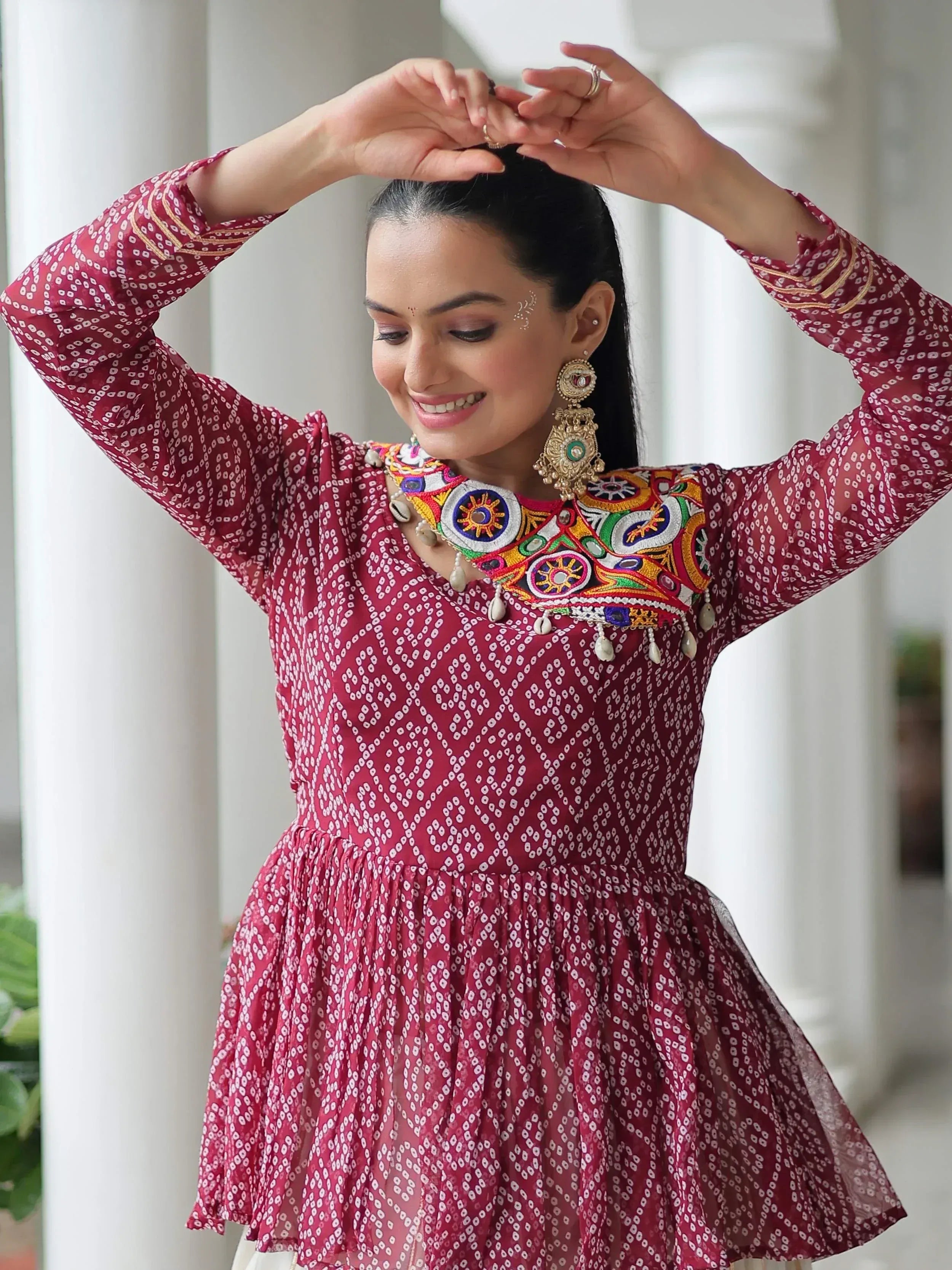 Woman in maroon printed ethnic kurta with colorful embroidered neckline and jhumka earrings