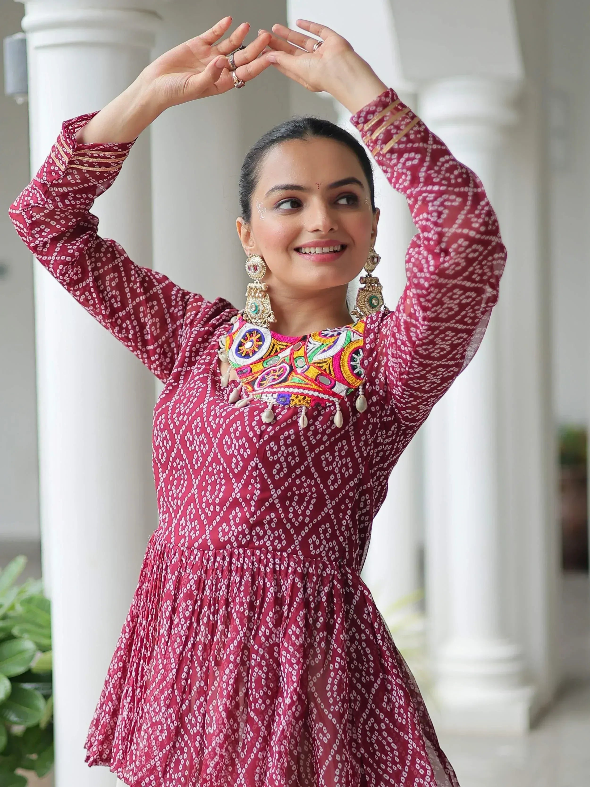 Woman in maroon ethnic dress with colorful embroidery and traditional jewelry