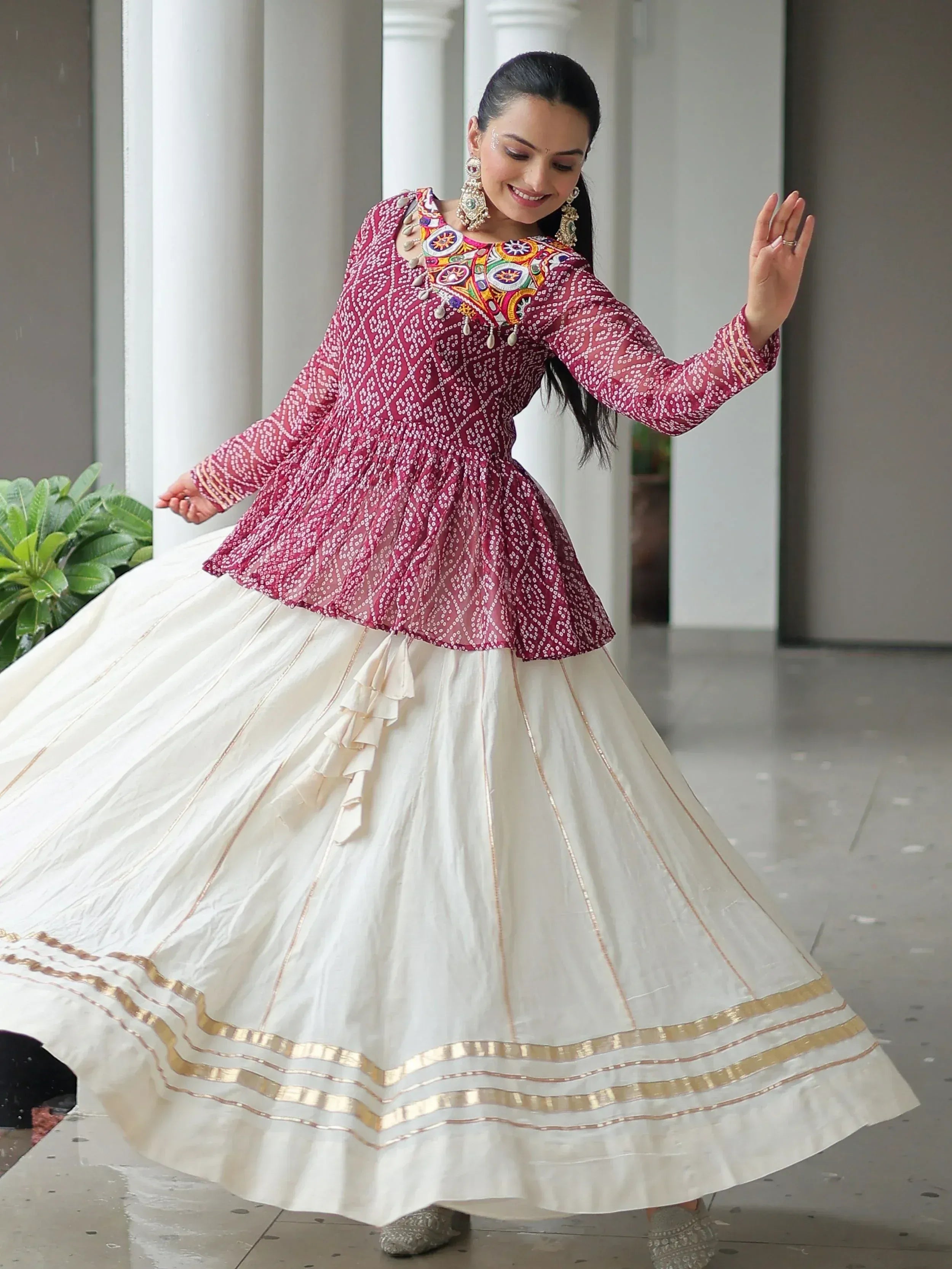 Woman in maroon embroidered top and white flared skirt, Indian ethnic wear for festive occasions