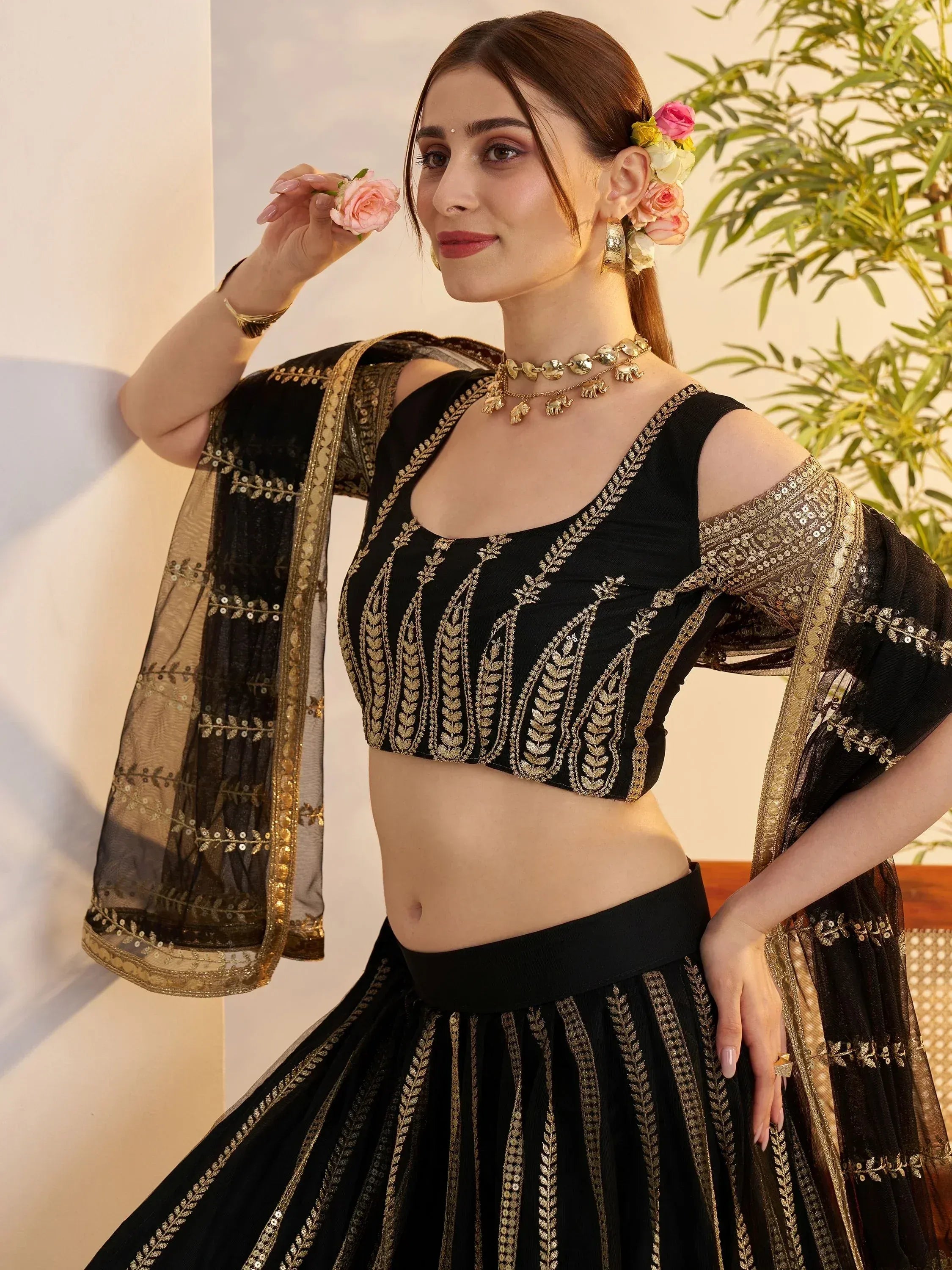 Black and gold embroidered lehenga choli with floral hair accessories and statement jewelry