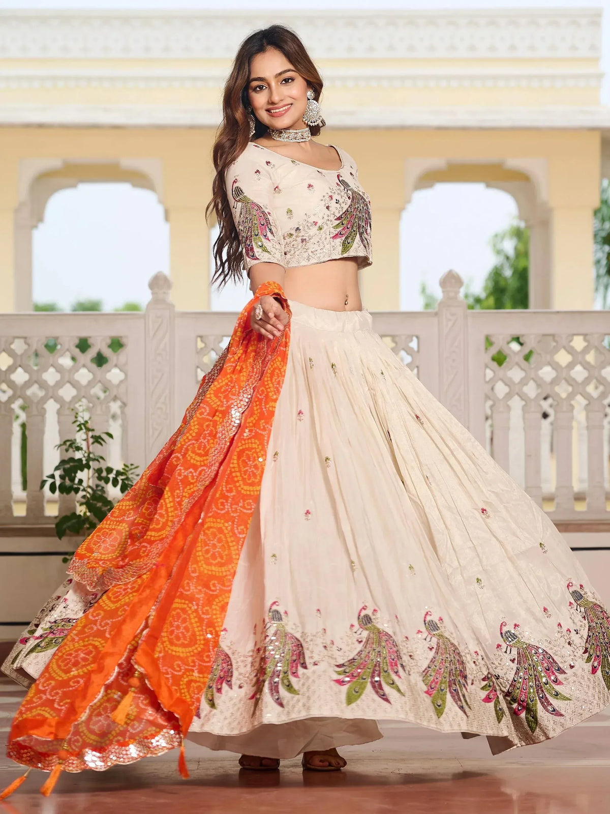Woman in cream lehenga choli with peacock embroidery and orange dupatta, Indian ethnic wear