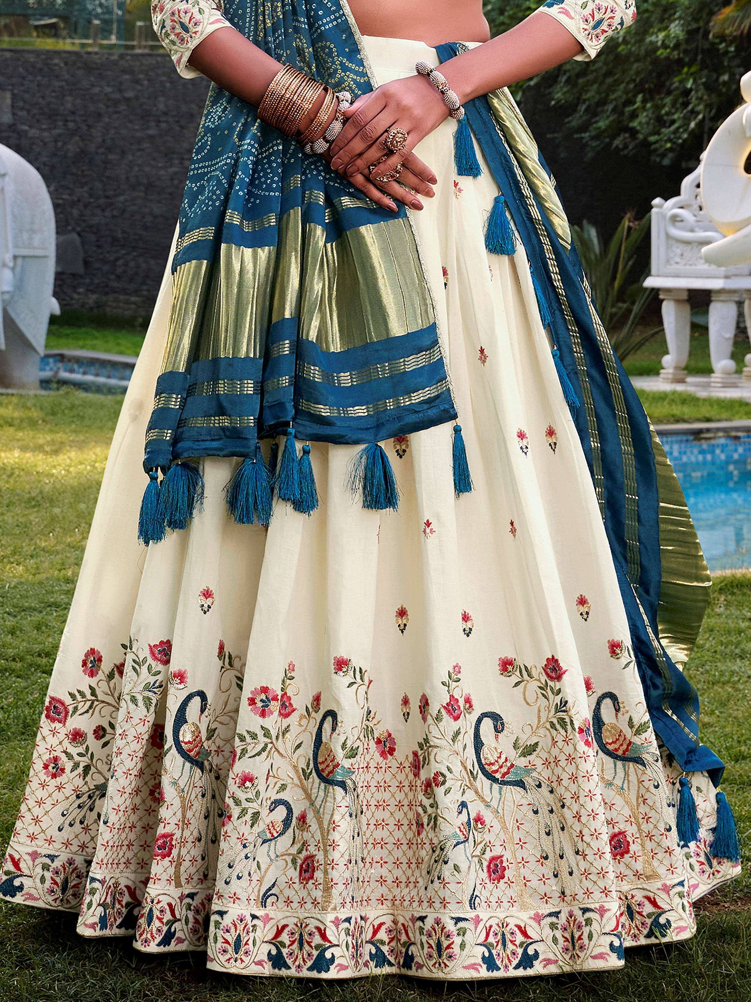 Cream lehenga with peacock embroidery, blue dupatta, and gold detailing for Indian ethnic wear