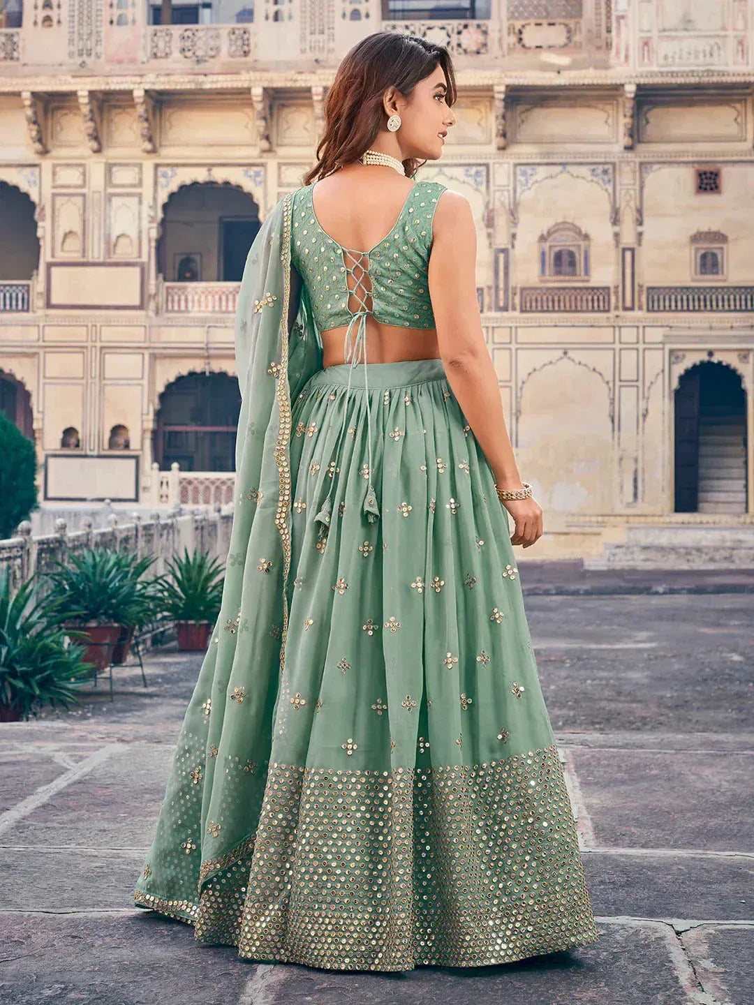 Mint green designer lehenga choli with gold embroidery and mirror work, perfect for Indian ethnic occasions.