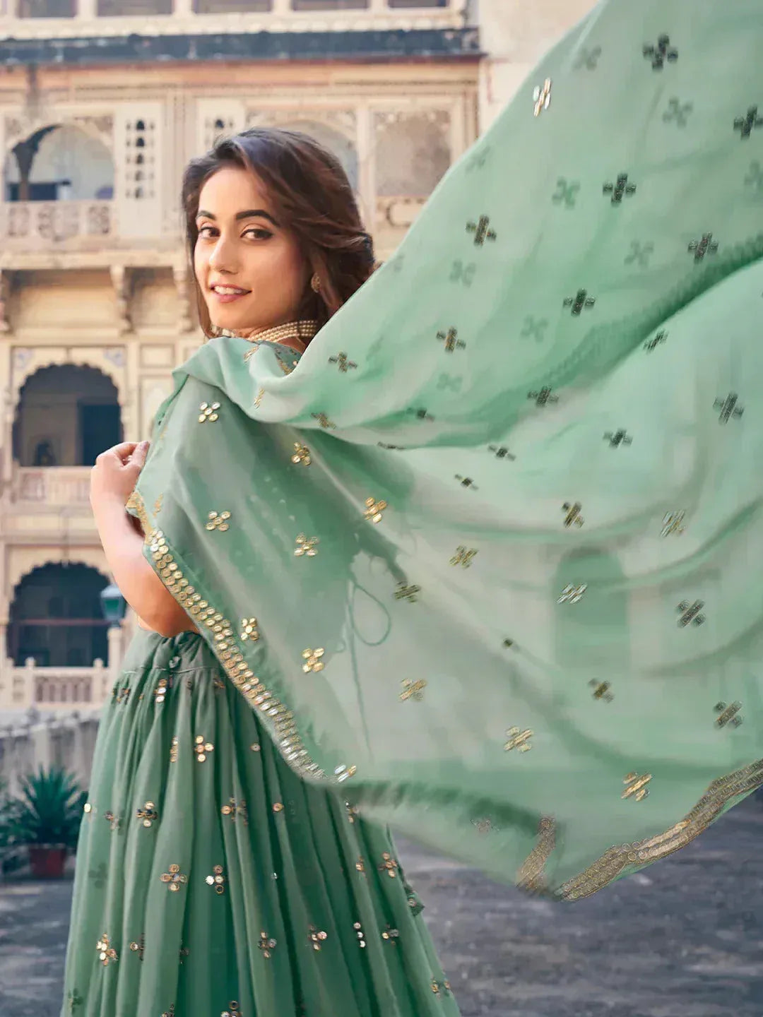 Woman in mint green embroidered lehenga choli with flowing dupatta, traditional Indian ethnic wear