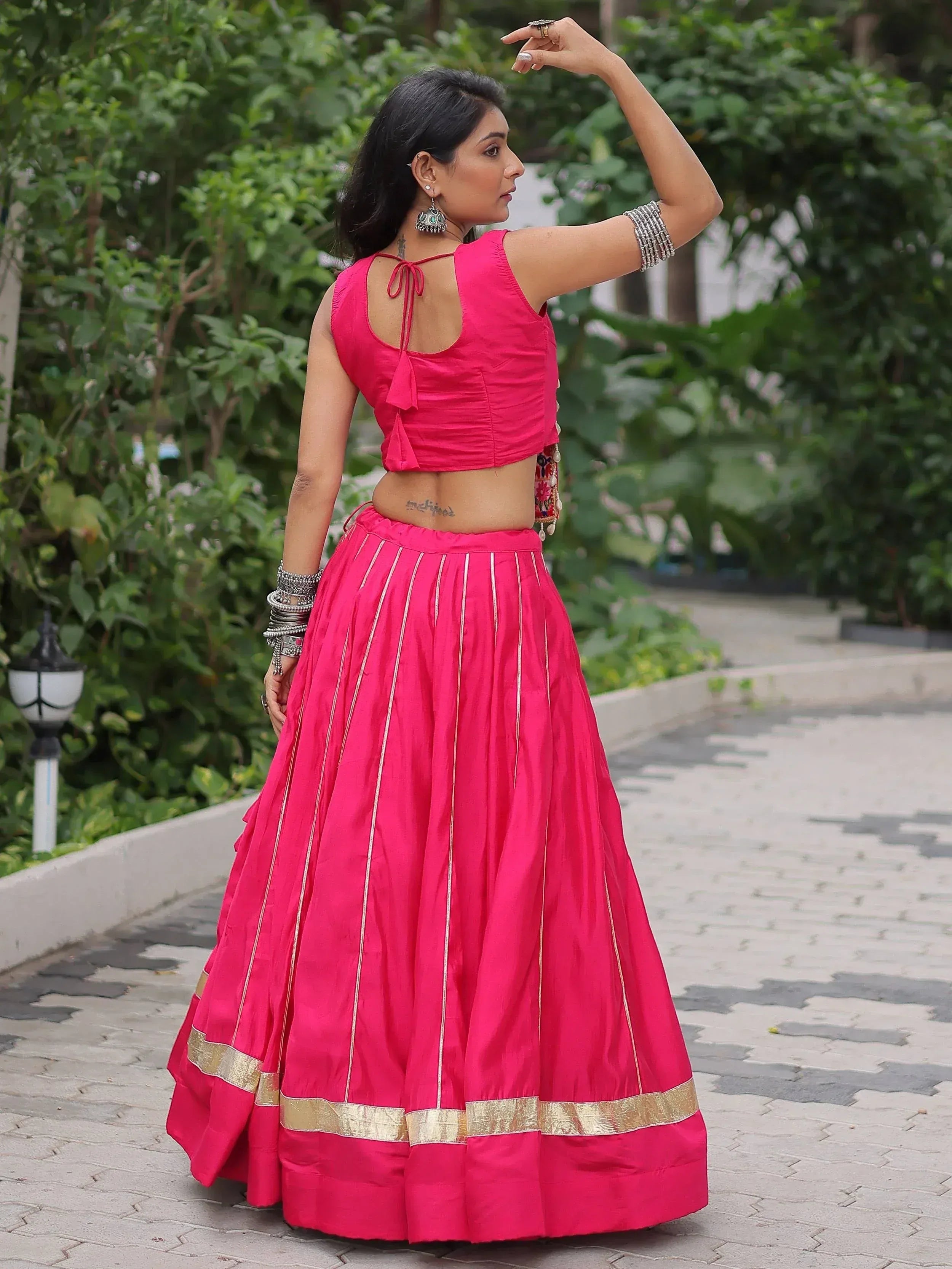 Woman in vibrant pink lehenga choli with gold trim, showcasing ethnic Indian wear for festive occasions