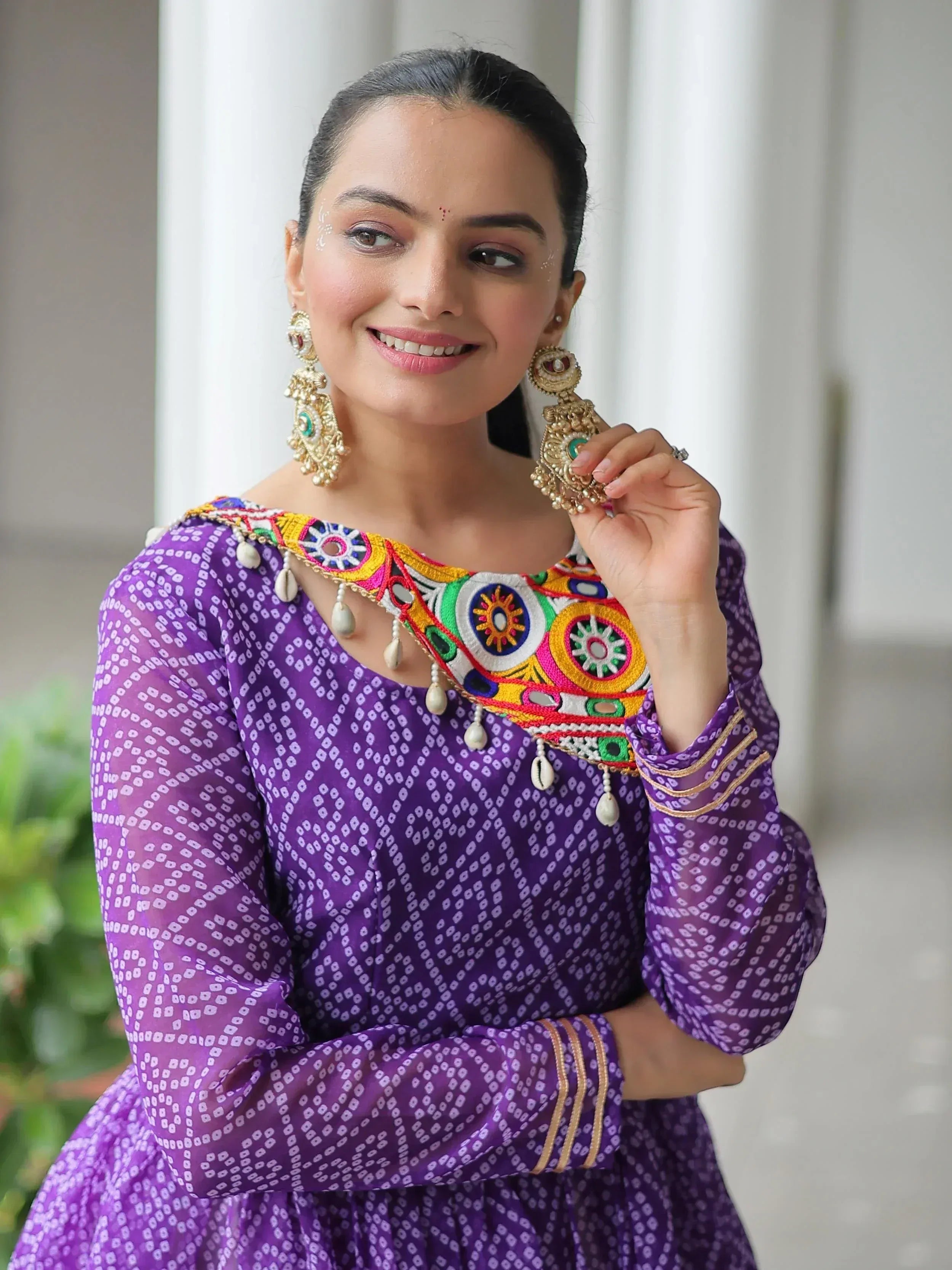 Purple ethnic gown with colorful mirror embroidery and traditional jewelry for Indian festive wear