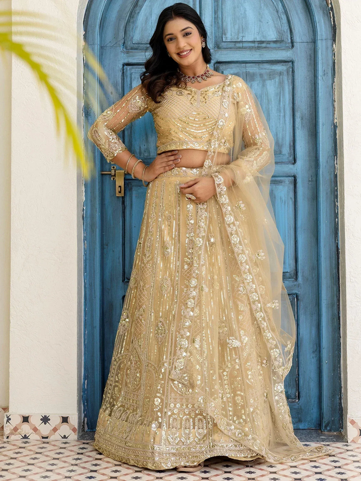 Elegant gold embroidered lehenga choli with sheer dupatta, perfect for Indian weddings and festive occasions.