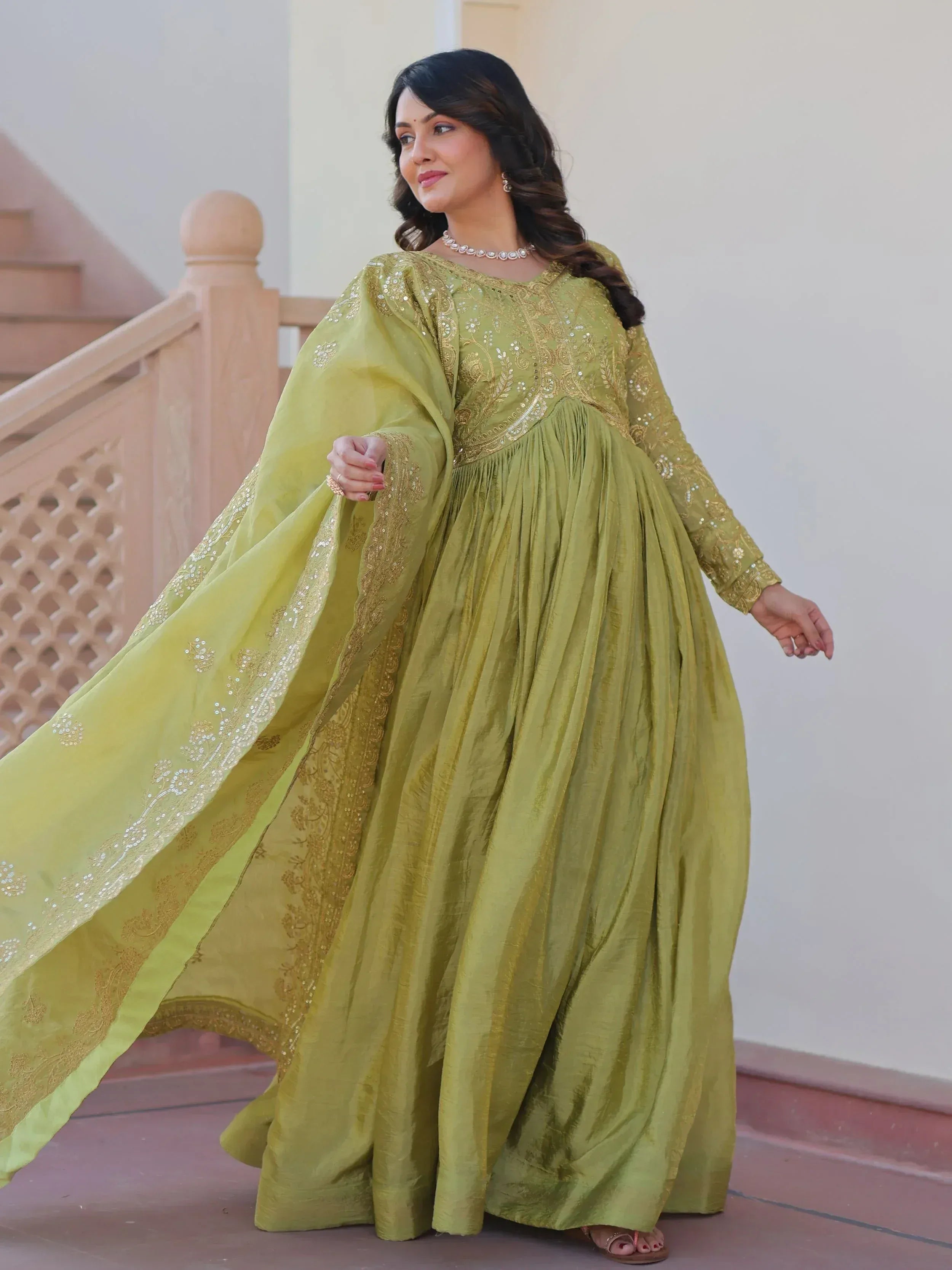 Elegant olive green ethnic gown with gold embroidery and sequins, perfect for Indian festive occasions.
