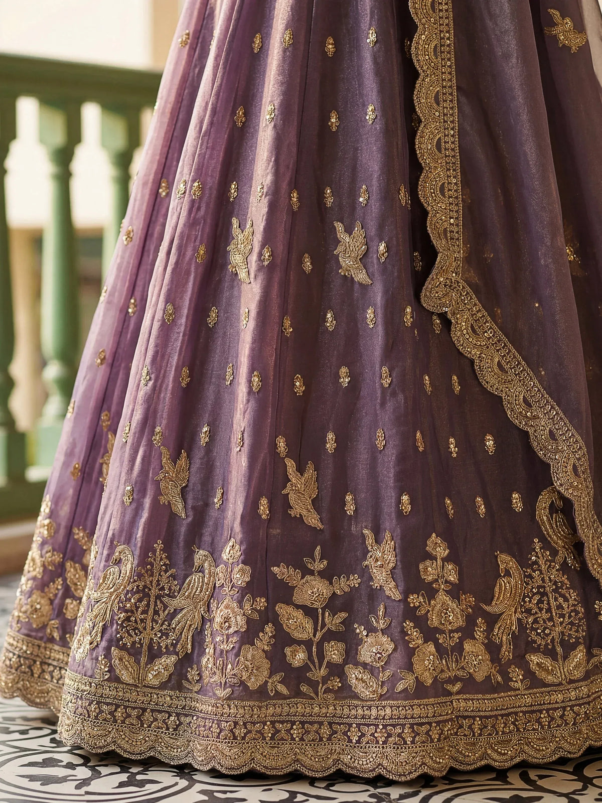 Close-up of a purple designer lehenga with intricate gold floral and bird embroidery