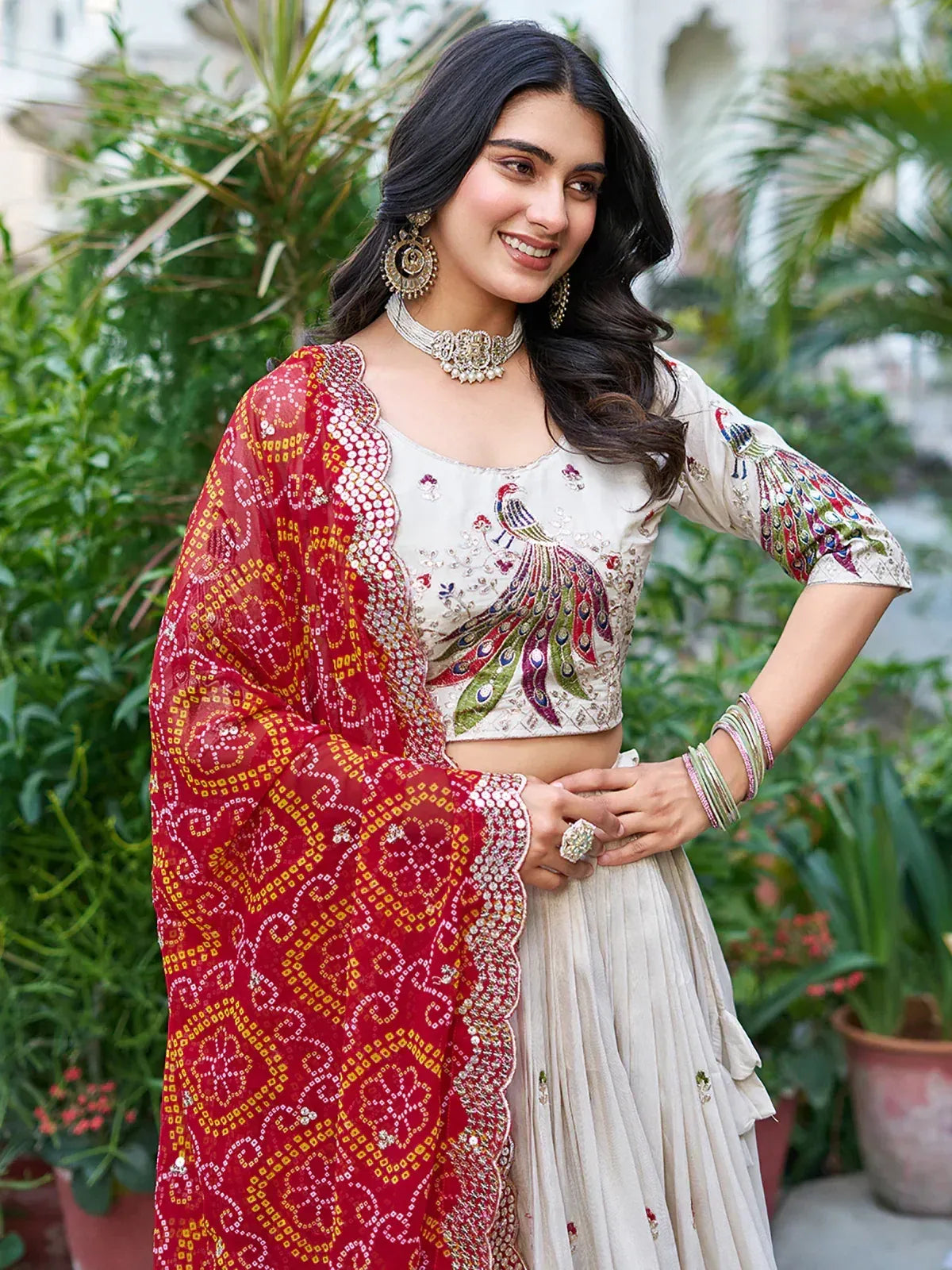 Elegant Indian lehenga choli with peacock embroidery, red dupatta, and traditional jewelry for festive occasions