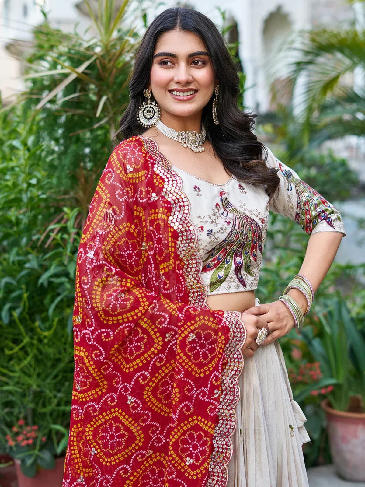 Elegant Indian ethnic wear with peacock embroidery, red dupatta, and traditional jewelry for festive occasions