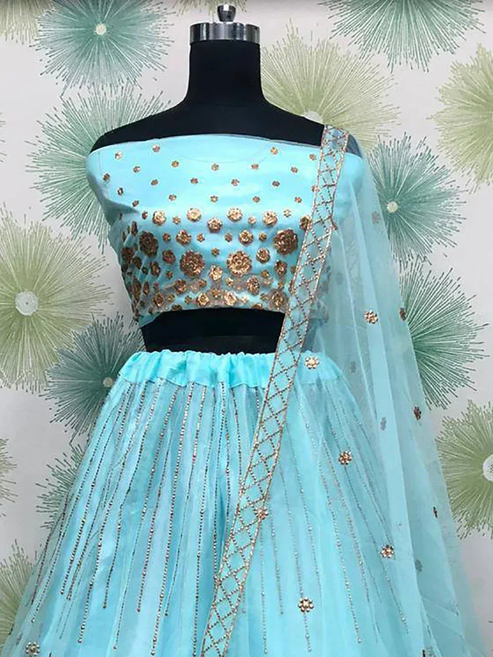 Light blue designer lehenga choli with gold floral embroidery and sheer dupatta, perfect for ethnic occasions.