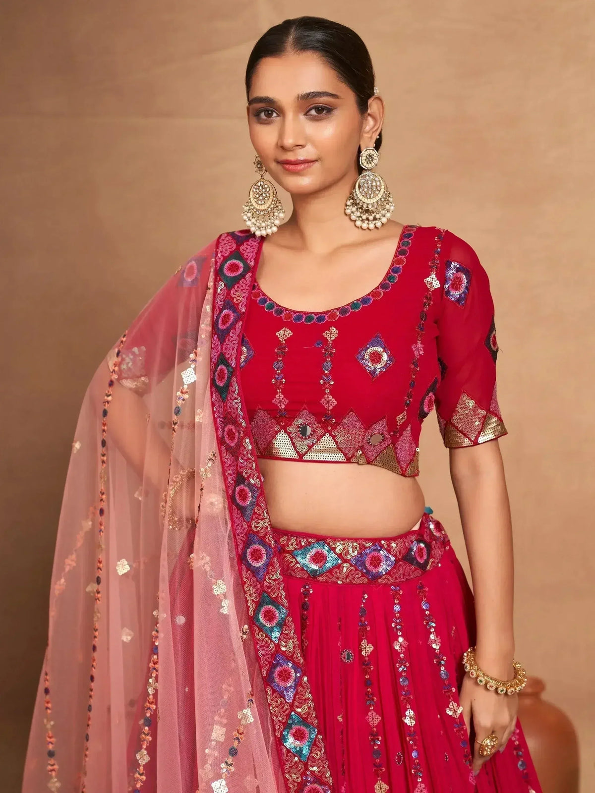 Red embroidered lehenga choli with mirror work, paired with sheer dupatta for festive occasions