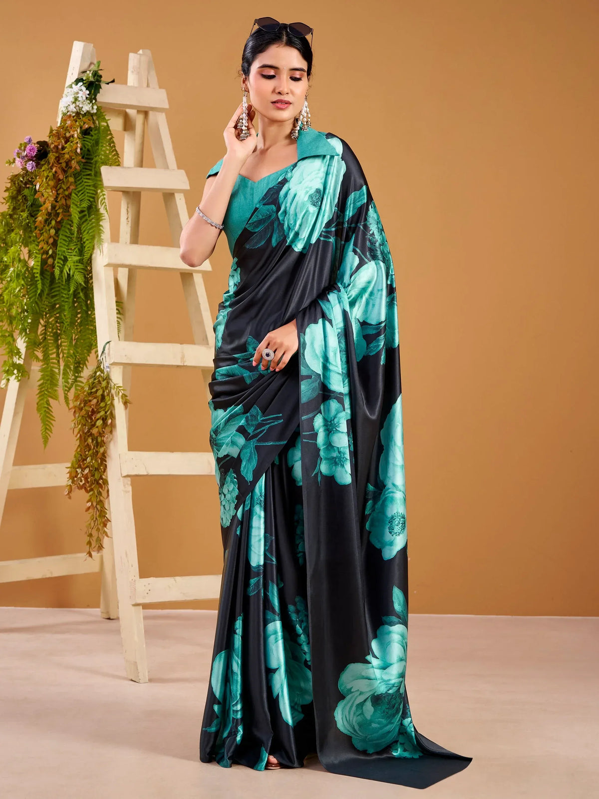 Woman wearing a black and teal floral print designer satin saree
