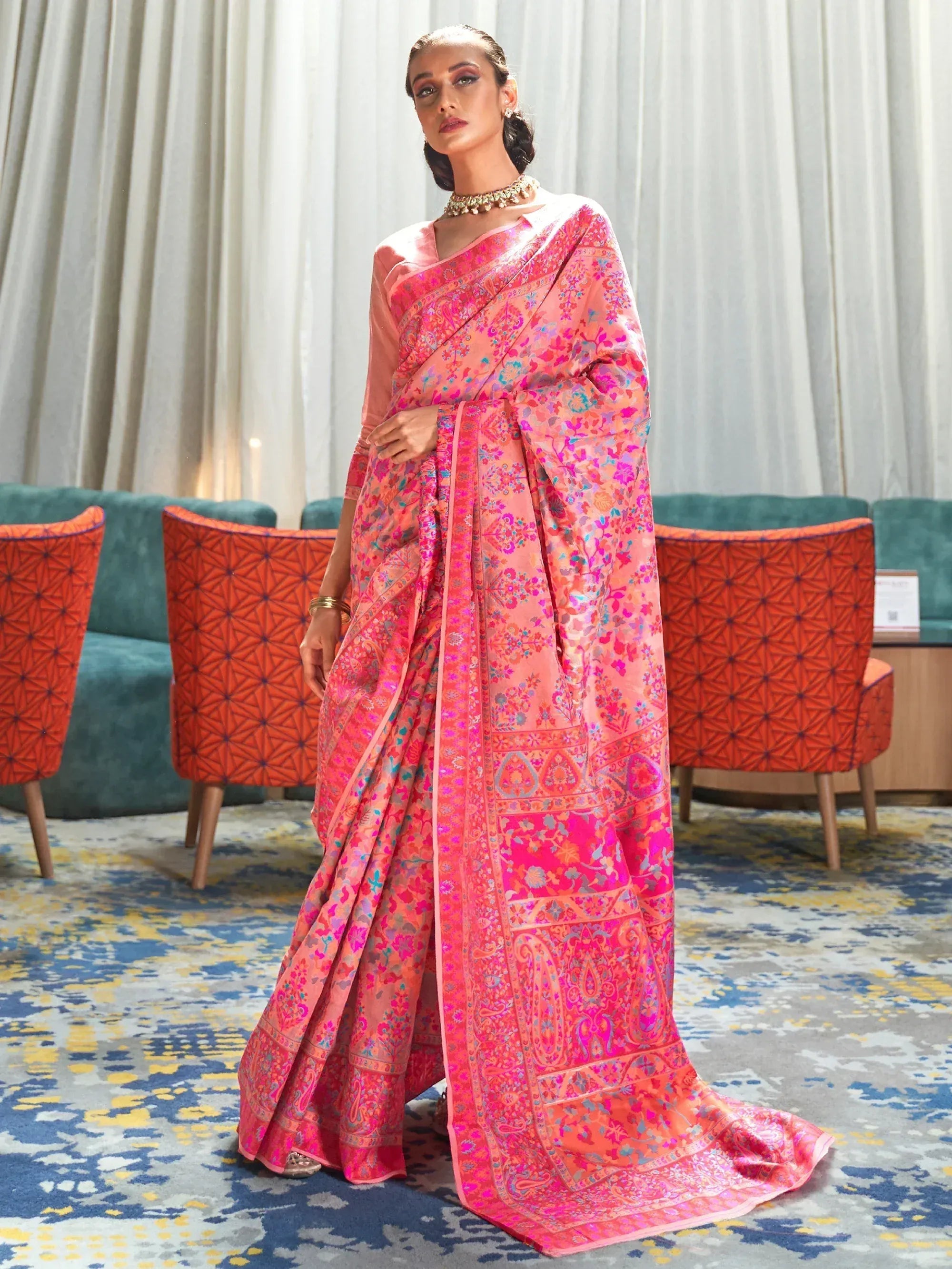 Pink floral printed saree with paisley border, styled with gold jewelry for ethnic occasions