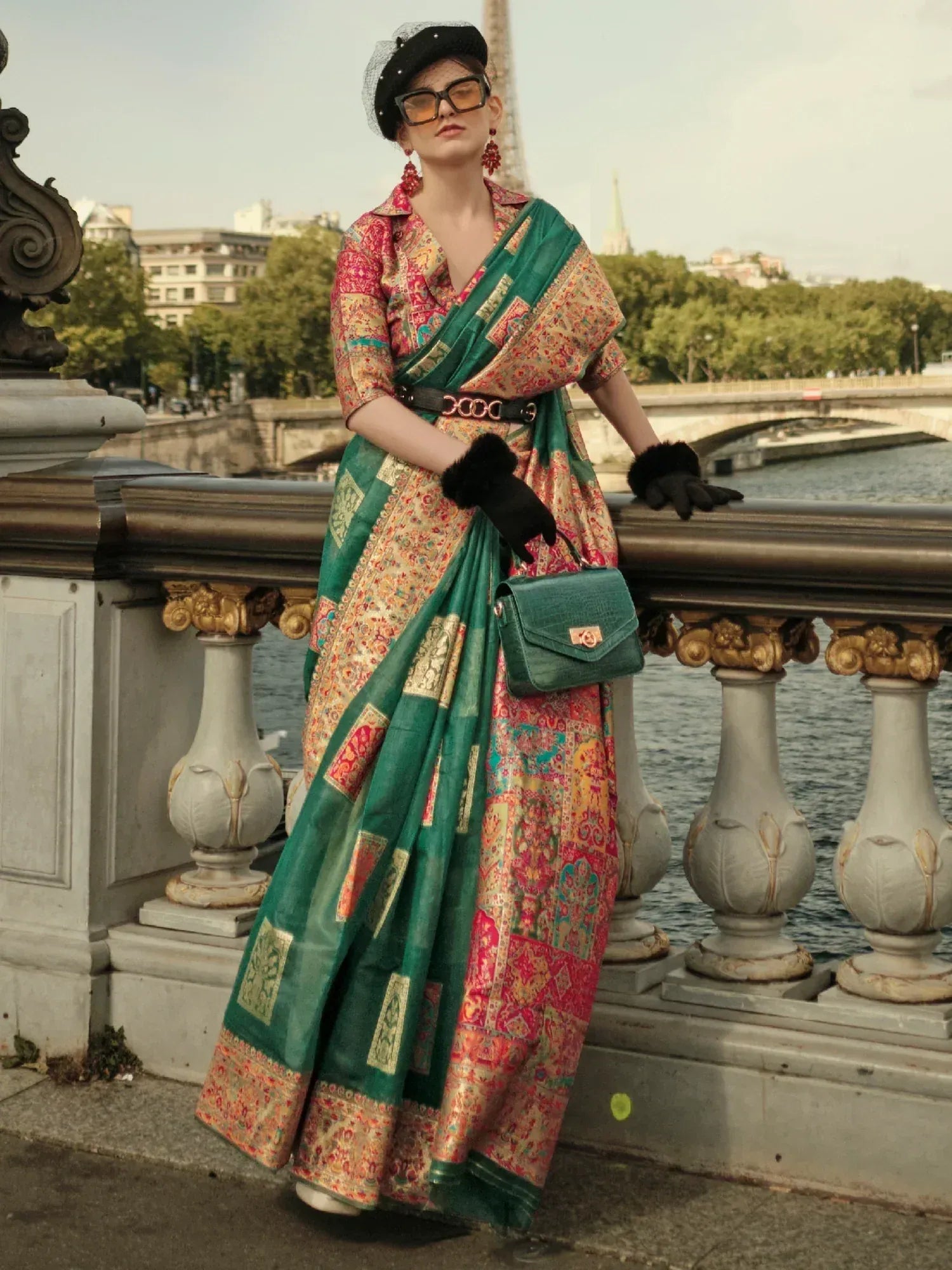 Woman in vibrant printed saree with green border, Paris bridge backdrop, stylish ethnic wear