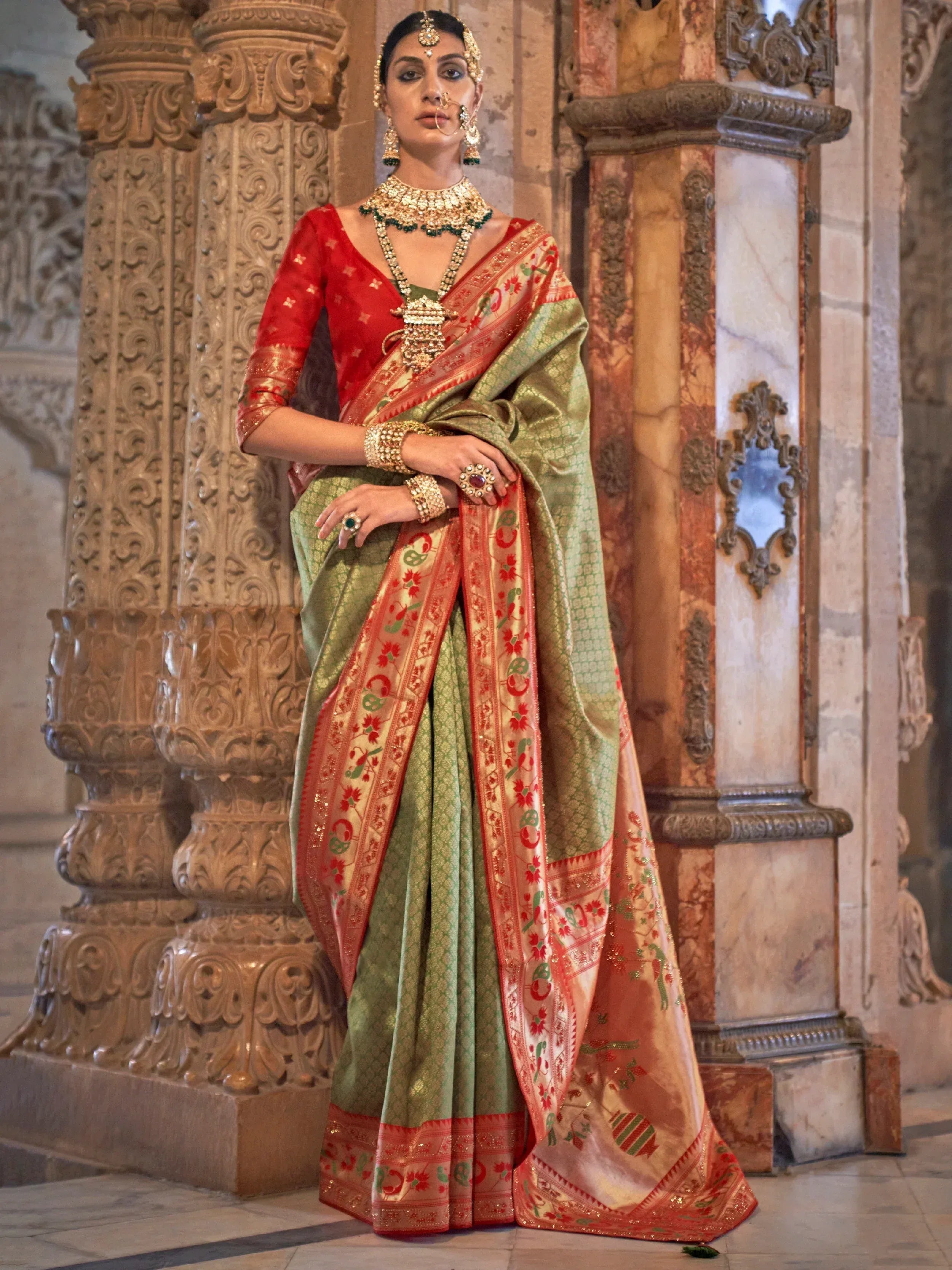 Elegant green and red designer saree with gold embroidery, paired with traditional Indian jewelry, perfect for ethnic occasions.