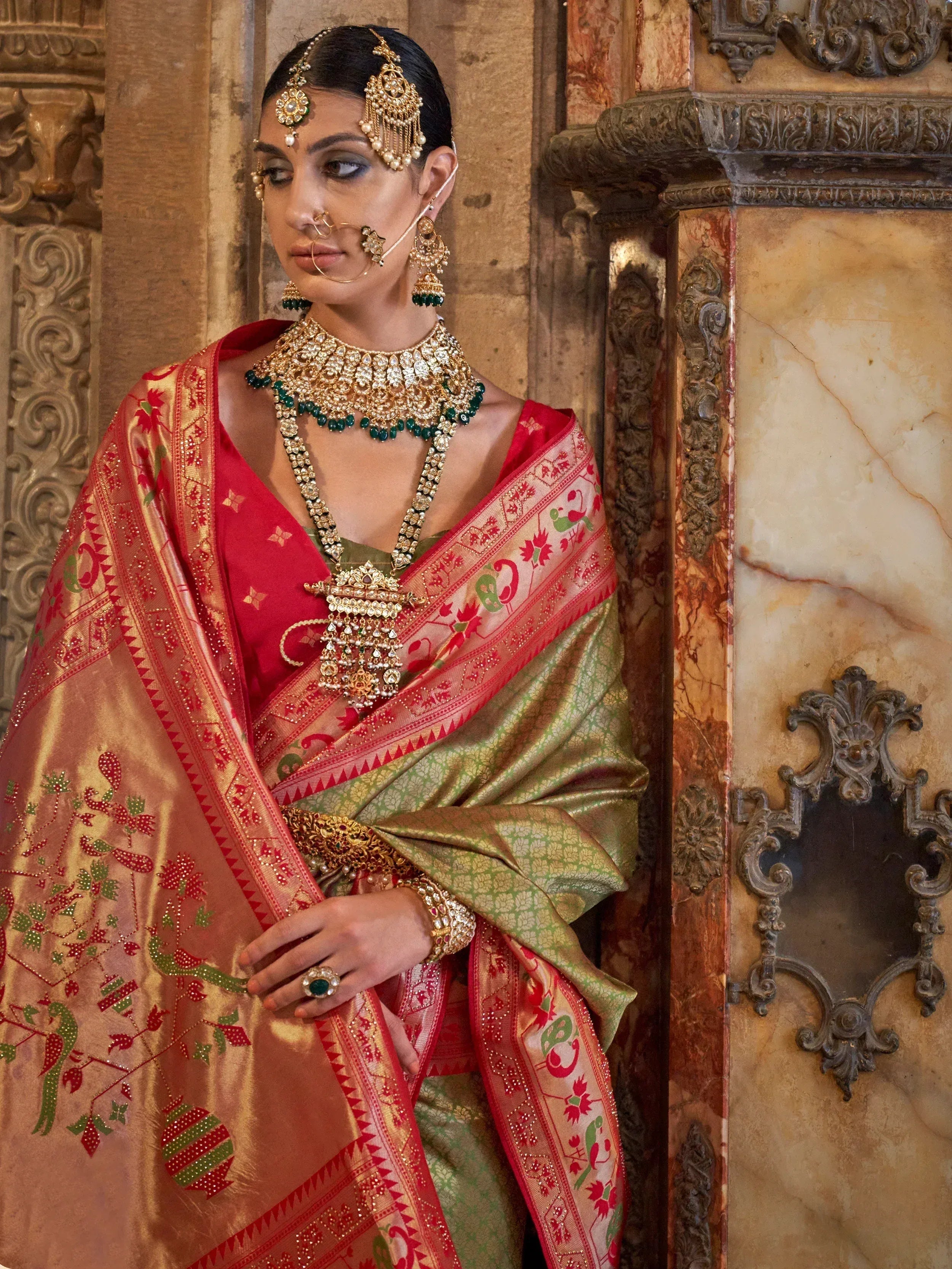Elegant Indian bride in red and green embroidered saree with heavy gold jewelry, traditional ethnic wear