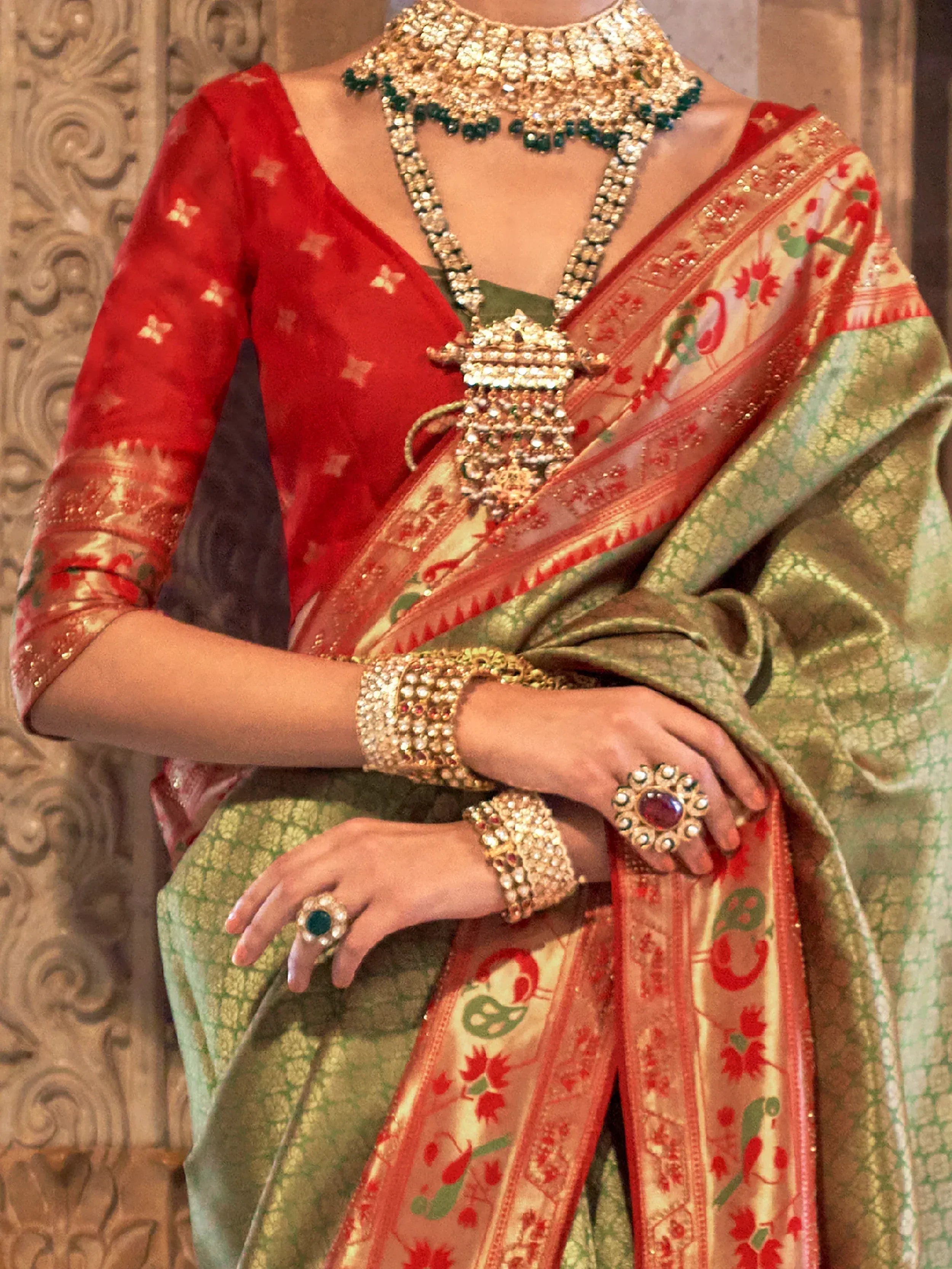 Red and green ethnic saree with gold jewelry, perfect for Indian weddings or festive occasions.