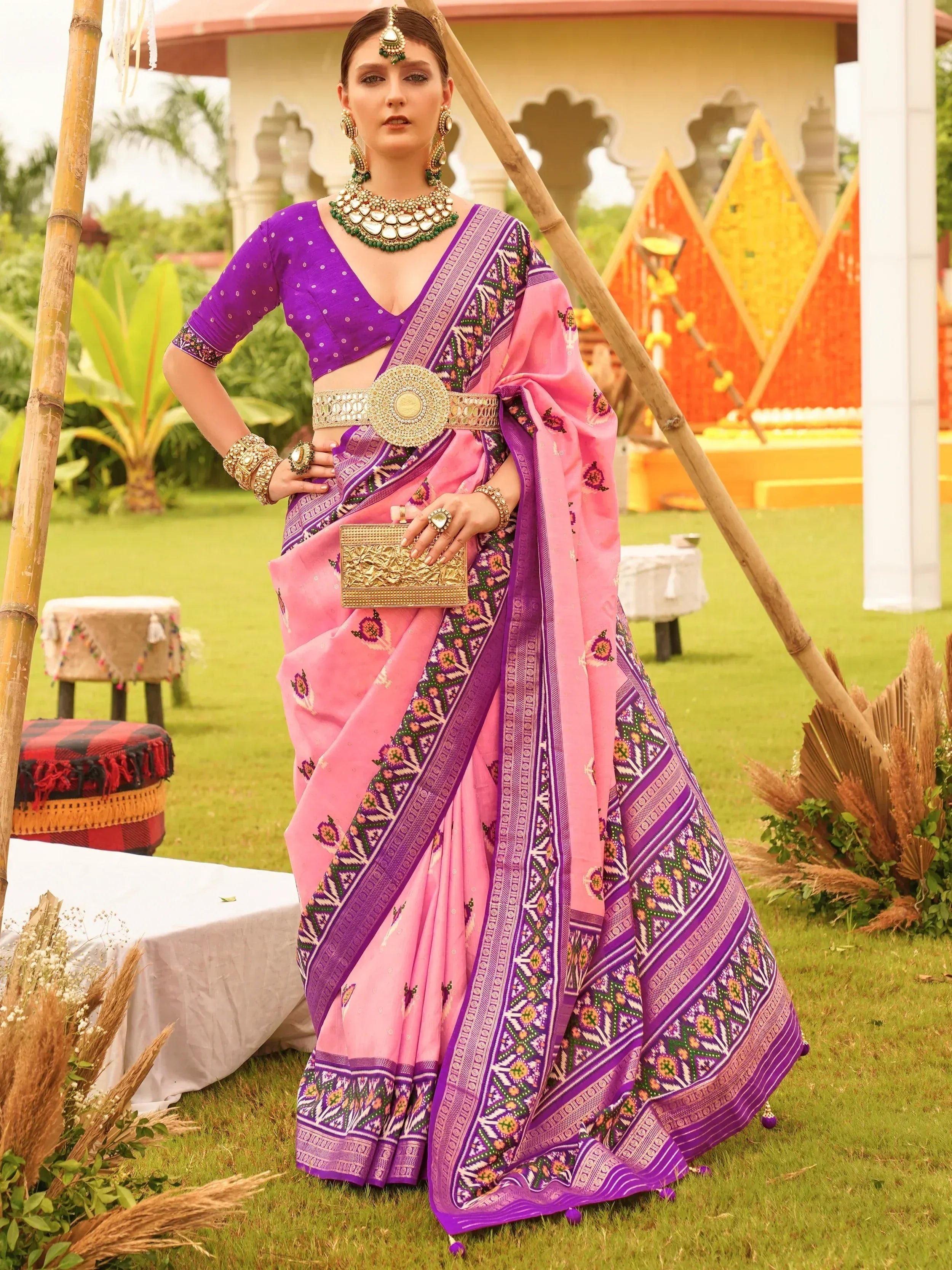 Pink and purple designer saree with ethnic print, gold belt, and traditional jewelry for Indian occasions