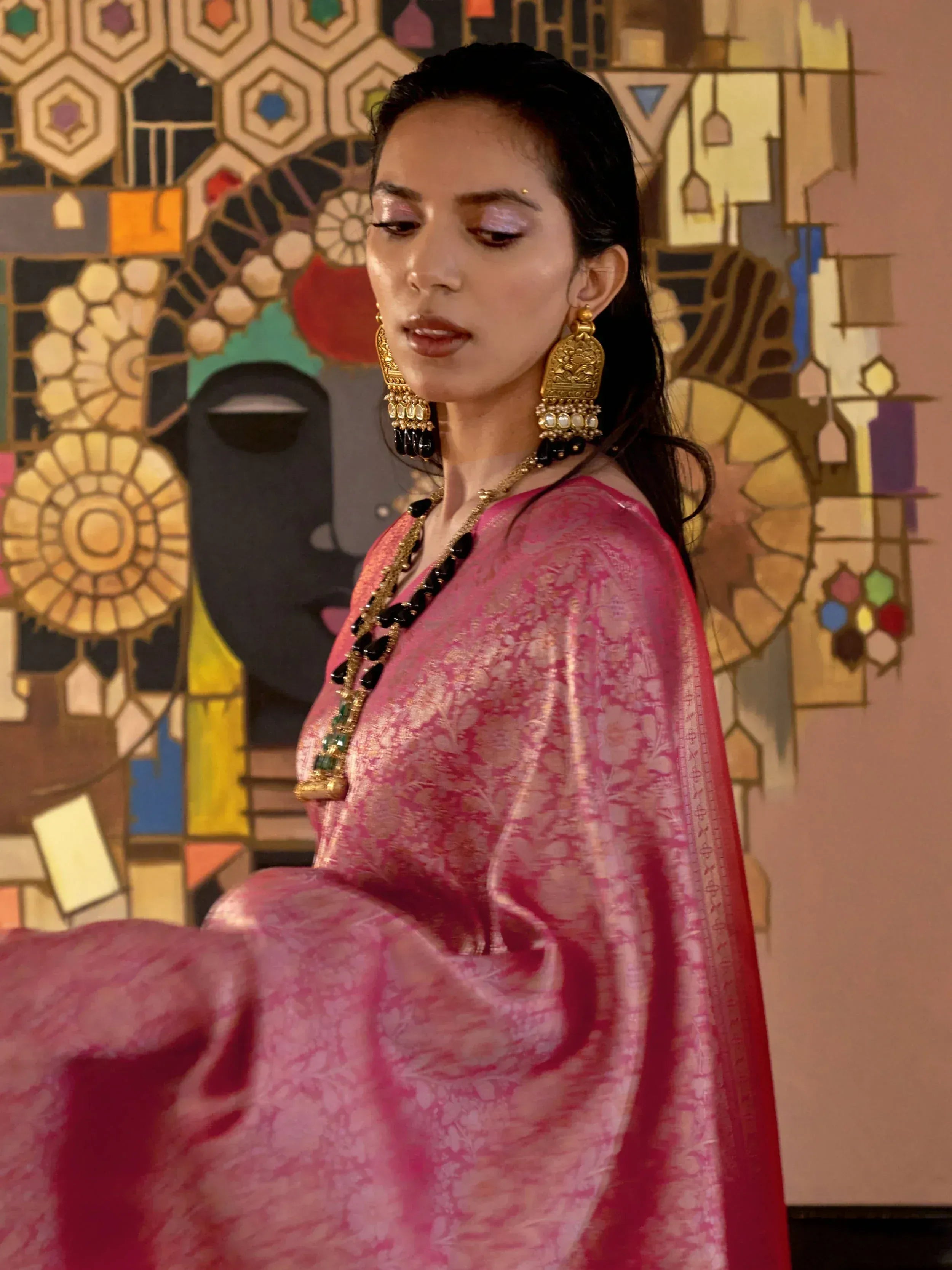 Woman in pink floral ethnic gown with gold jewelry, styled for Indian occasions