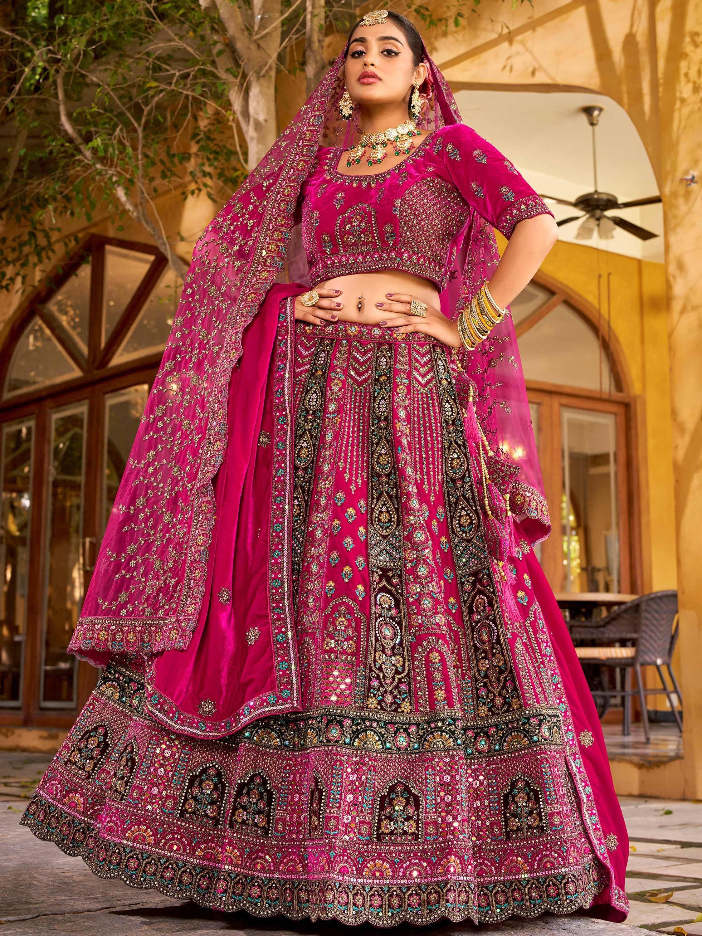 Fuchsia velvet designer lehenga choli with heavy embroidery, perfect for Indian weddings and festive occasions.