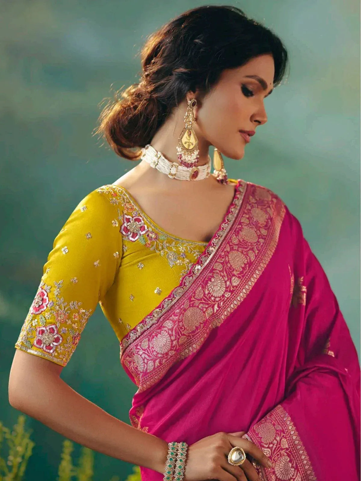 Woman in vibrant pink saree with gold border and yellow embroidered blouse, traditional Indian ethnic wear