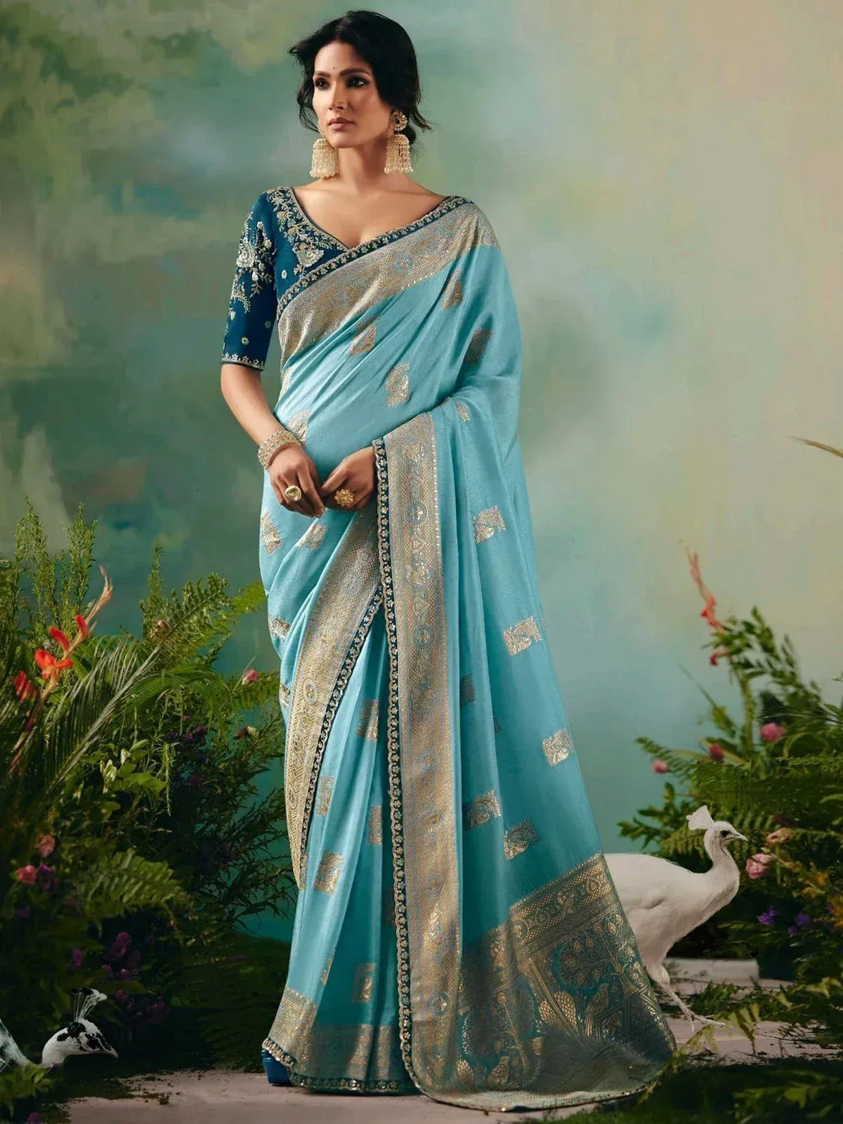 Elegant light blue saree with gold embroidery and matching blouse, styled with statement jewelry for Indian ethnic wear.