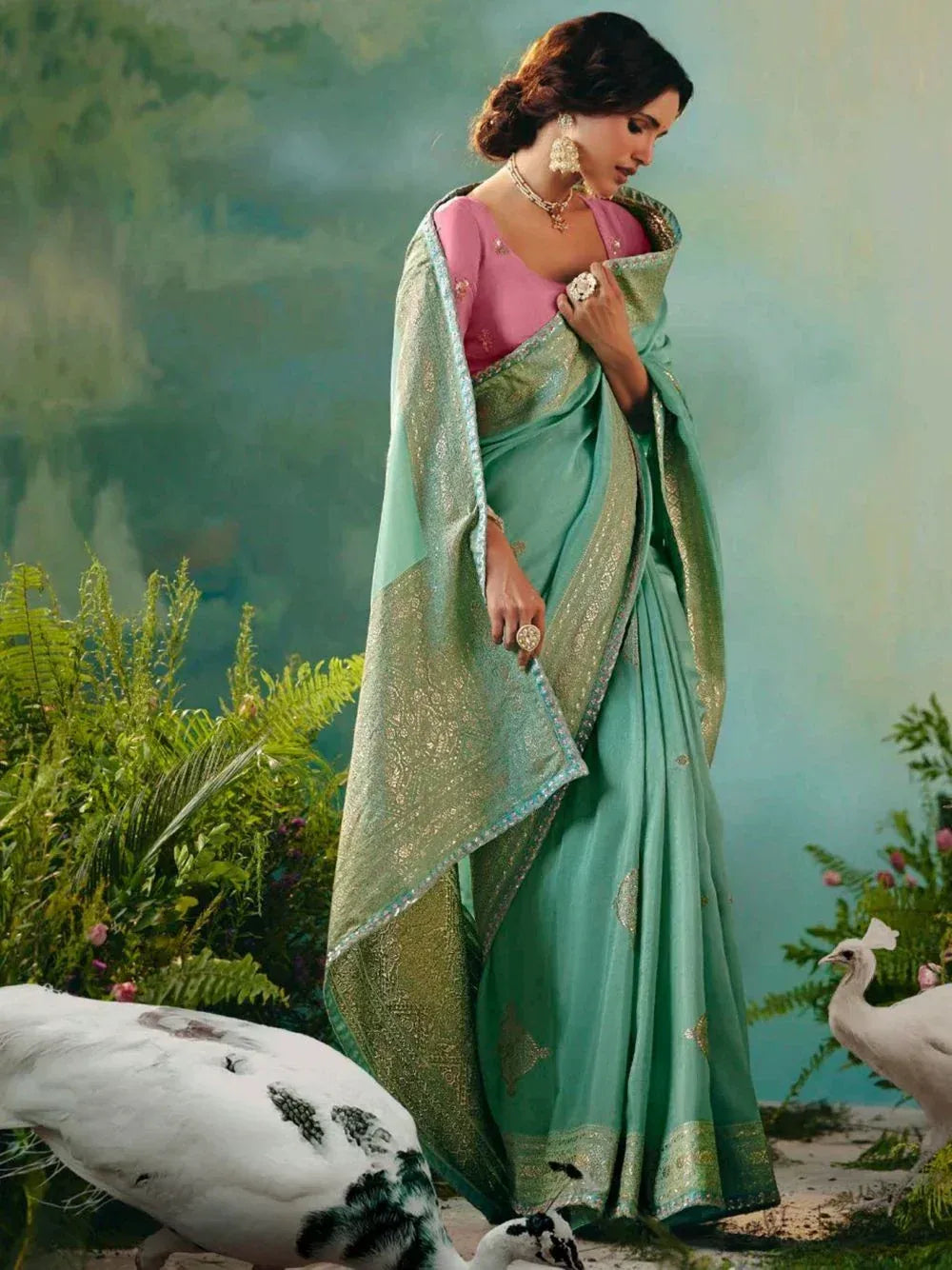 Elegant mint green saree with gold embroidery, paired with pink blouse, styled with peacocks in garden setting