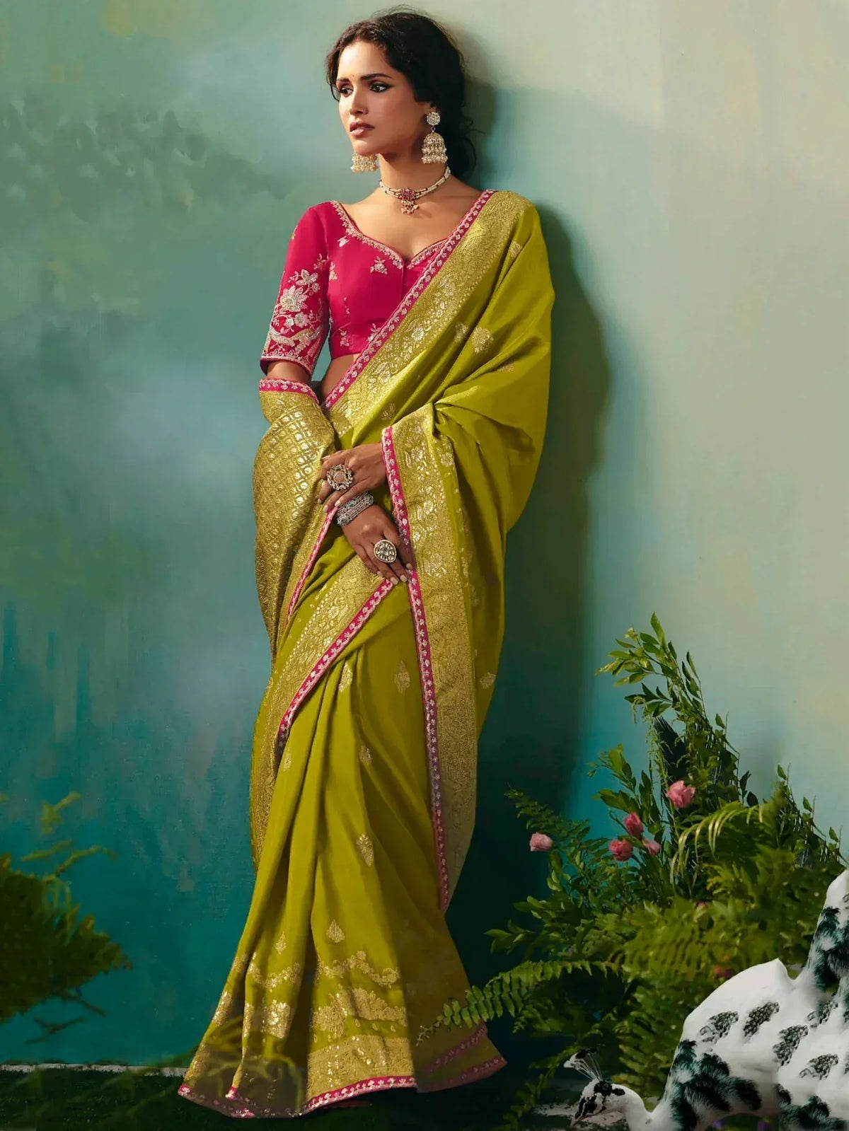 Woman in vibrant green saree with gold embroidery and pink blouse, styled with traditional jewelry for ethnic occasions