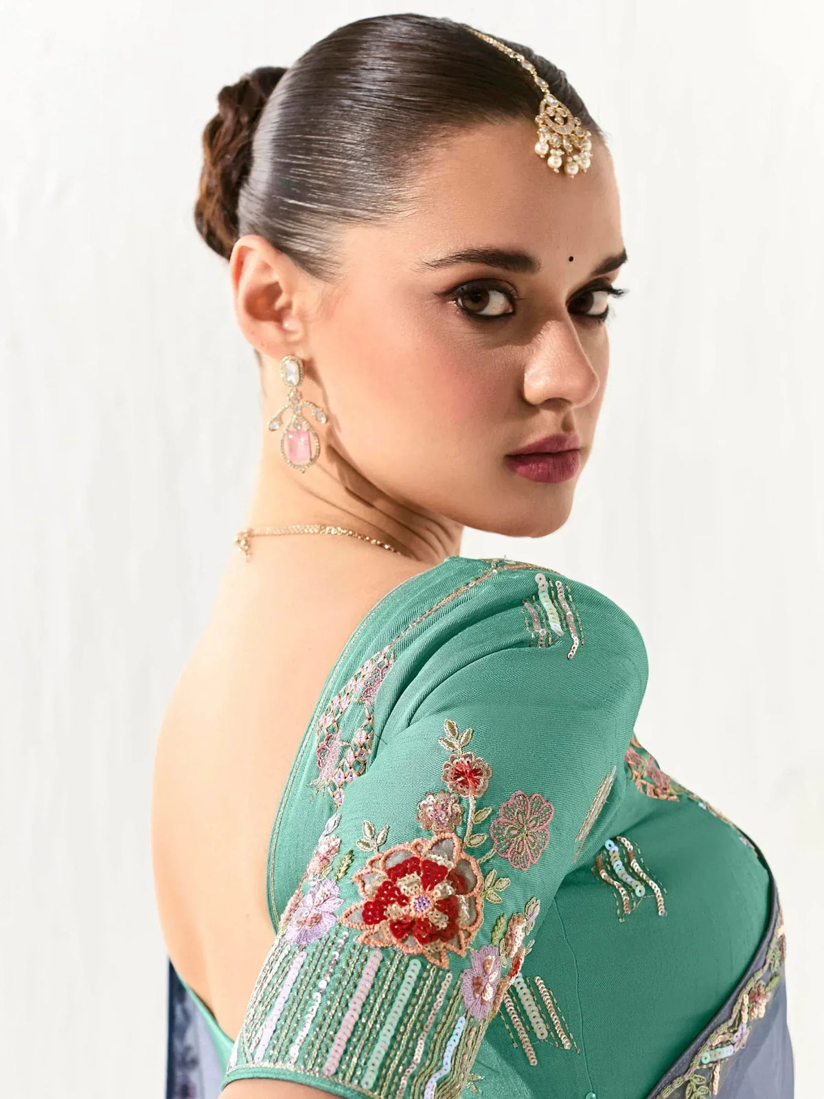 Woman in green embroidered saree blouse with floral sequin detailing, traditional Indian ethnic wear