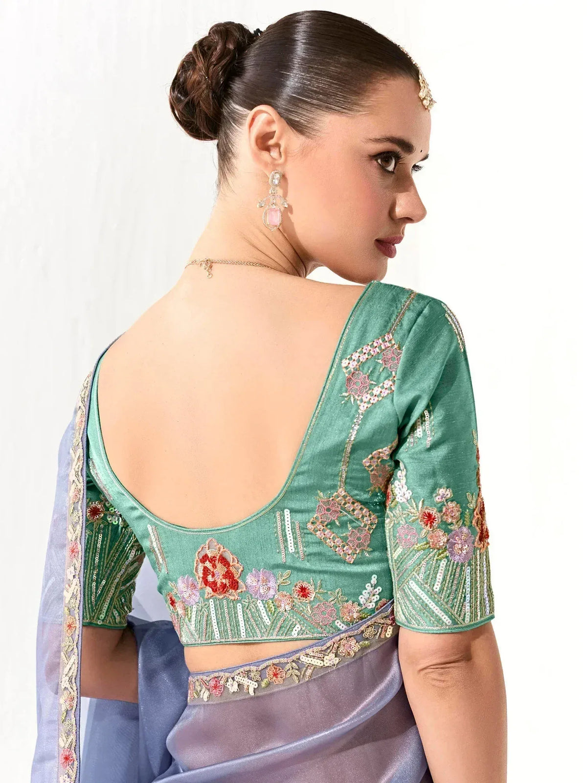 Green embroidered blouse with floral designs, paired with a lavender saree, showcasing elegant Indian ethnic wear.